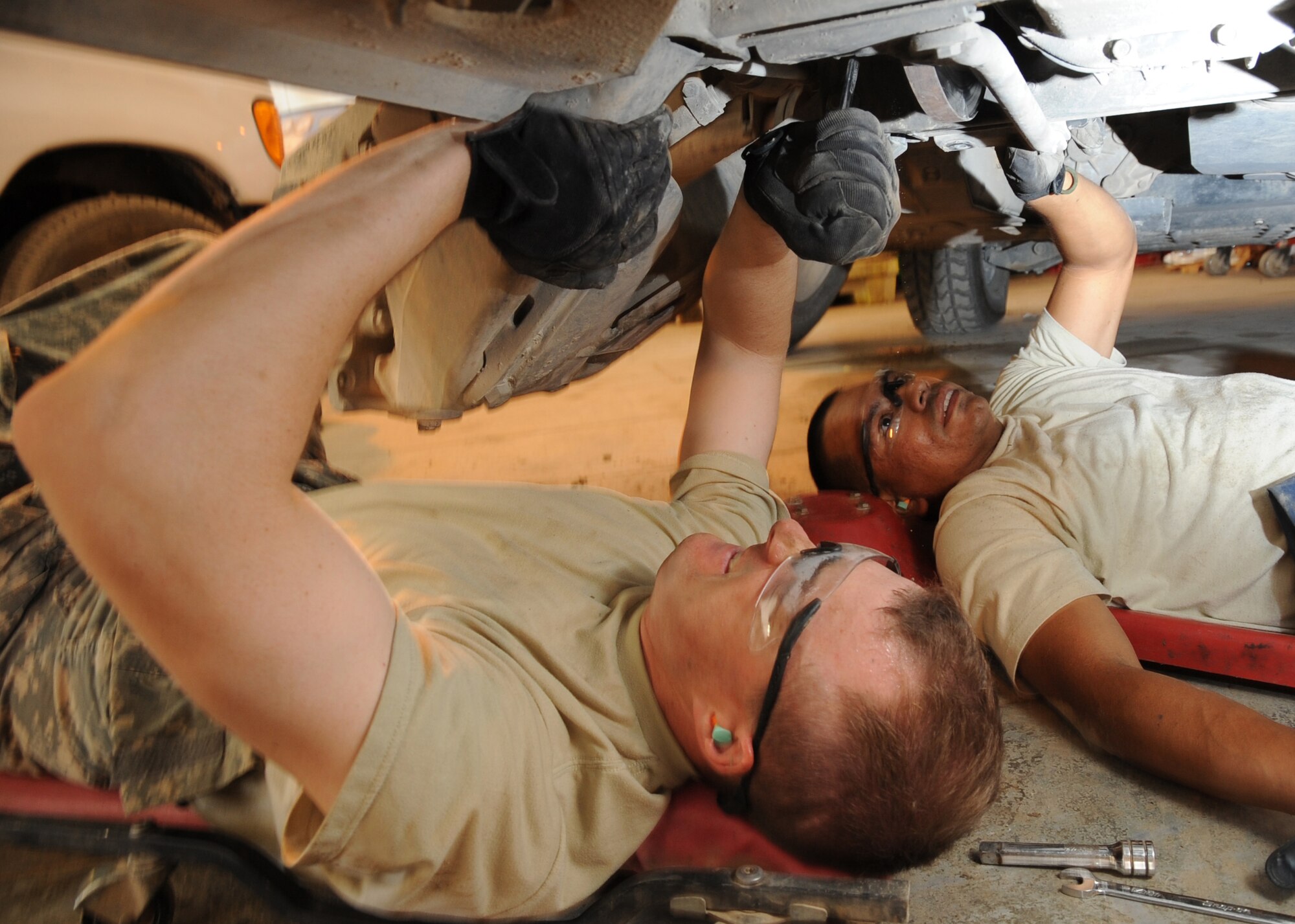 SATHER AIR BASE, Iraq -- Staff Sgt. Luis Monterrosa (right), 447th Expeditionary Logistics Readiness Squadron vehicle equipment journeyman, observes Chaplain (Capt.) Chad Montgomery, 447th Air Expeditionary Group, using a wrench to remove the rotor and brake pads from a Humvee here Sept. 11, 2009. Chaplain Montgomery has made it his goal to get involved by helping Airmen with their daily missions and training during his deployment. Sergeant Monterrosa is deployed from Keesler Air Force Base, Miss., and is a native of Los Angeles, Calif. Chaplain Montgomery is deployed from Lackland AFB, Texas, and is a native of Newtown Square, Pa. (U.S. Air Force photo/Tech. Sgt. Johnny L. Saldivar/Released)