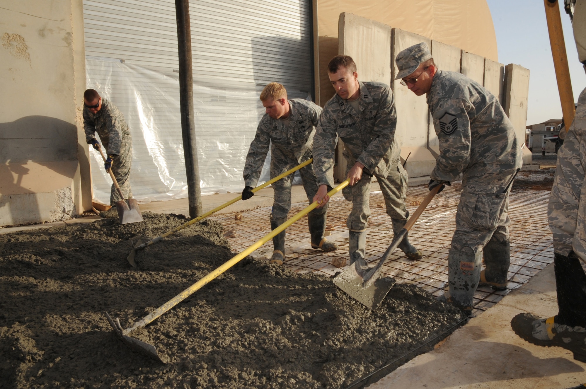 SATHER AIR BASE, Iraq -- Air Force Chaplain (Capt.) Chad Montgomery, 447th Air Expeditionary Group, helps 447th Expeditionary Civil Engineer Squadron personnel level concrete for a sidewalk here Sept. 11, 2009. Chaplain Montgomery has made it his goal to get involved by helping Airmen with their daily missions and training during his deployment. Chaplain Montgomery is deployed from Lackland Air Force Base, Texas and is a native of Newtown Square, Pa. (U.S. Air Force photo/Tech. Sgt. Johnny L. Saldivar)