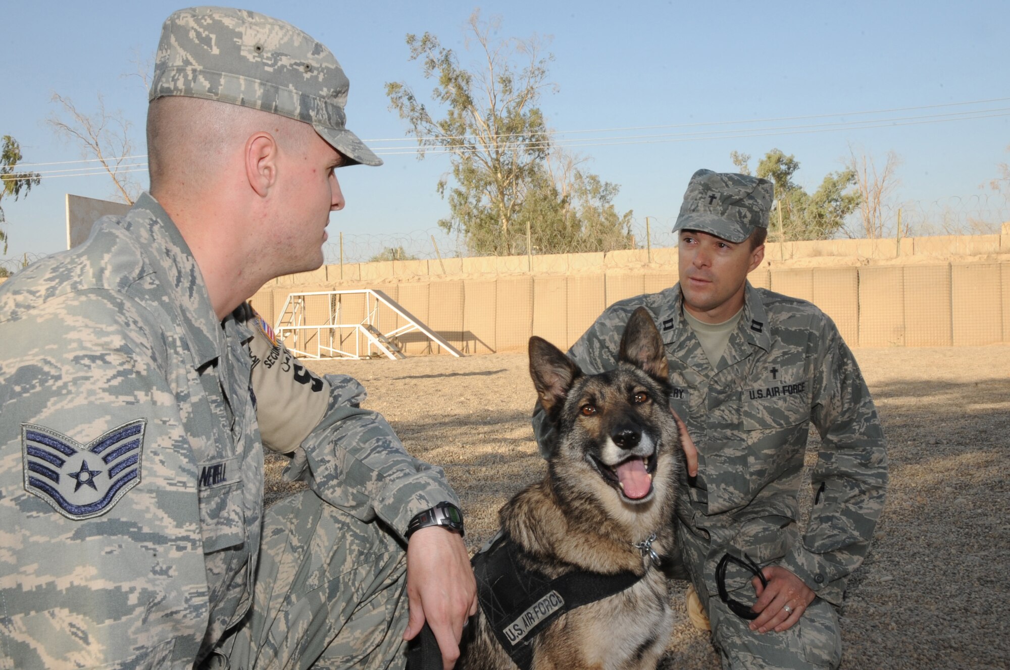 SATHER AIR BASE, Iraq -- Air Force Chaplain (Capt.) Chad Montgomery, 447th Air Expeditionary Group, takes time here to visit with Air Force Staff Sgt. David Newell, 447th Expeditionary Security Forces Squadron K-9 handler, and his German Sheppard partner Helena Sept. 10, 2009. Chaplain Montgomery has made it his goal to get involved by helping Airmen with their daily missions and training during his deployment. He is deployed from Lackland Air Force Base, Texas, and is a native of Newtown Square, Pa. Sergeant Newell is deployed from Fairchild AFB, Wash., and is a native of Colorado Springs, Colo. (U.S. Air Force photo/Tech. Sgt. Johnny L. Saldivar)