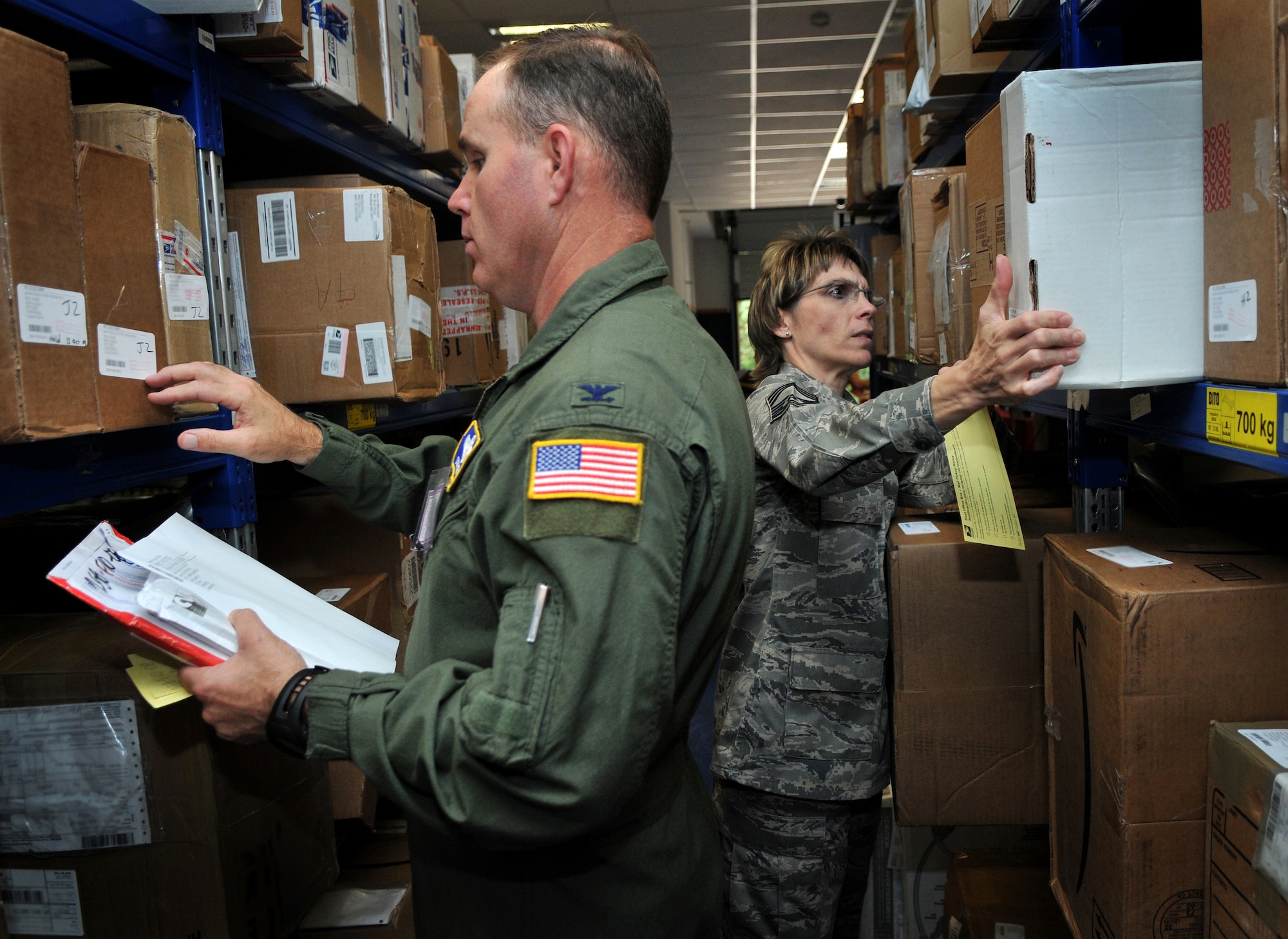 U.S. Air Force Col. Douglas Sevier, 86th Airlift Wing vice commander, left, and Chief Master Sgt. Sherri Olson find packages for customers at the North Side Post Office, Sept. 16, 2009, Ramstein Air Base, Germany. As Christmas season approaches volunteers play a big role in keeping lines short at the parcel pick-up window. (U.S. Air Force photo by Senior Airman Nathan Lipscomb)