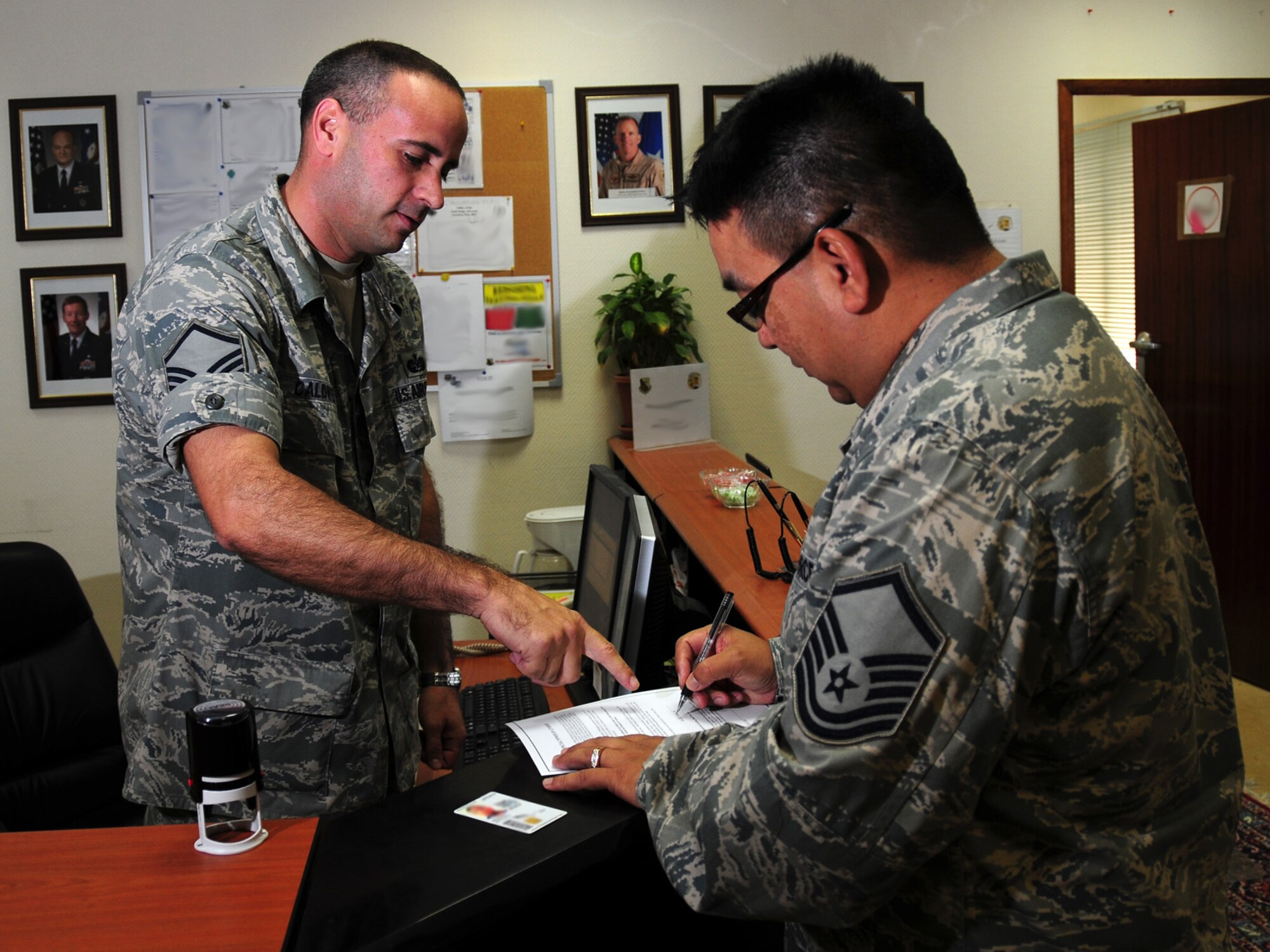Master Sgt. Mark Caldwell, 379th Air Expeditionary Wing Legal Office superintendent, assists Master Sgt. Nick Navarro, 379th Expeditionary Mission Support Group knowledge operations superintendent, with a power of attorney, here, Sept. 16. Sergeant Caldwell and Sergeant Navarro are both deployed from Hickam Air Force Base, Hawaii in support of Operations Iraqi and Enduring Freedom. (U.S. Air Force Photo/Tech. Sgt. Jason W. Edwards)