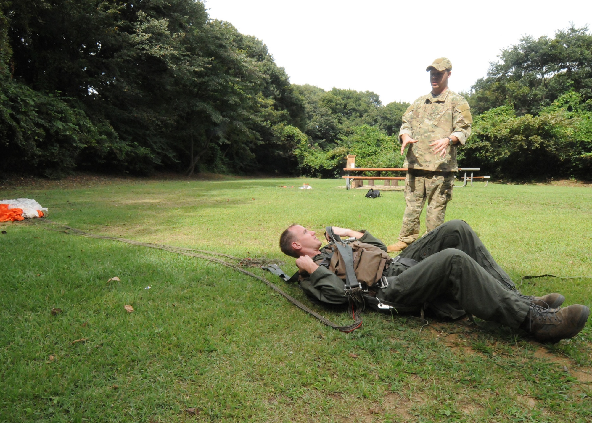 YOKOTA AIR BASE, Japan -- Staff Sgt. Benjamin Rosciglione, 374th Operations Support Squadron Survival, Evasion, Resistance and Escape specialist, (standing) and Capt. Brett Cassidy, 374th Operations Group executive officer and C-130 pilot, demonstrate techniques used following a parachute landing during combat survival refresher training recently at Tama Hills Recreation Area. (U.S. Air Force photo/Staff Sgt. Veronica Pierce)  