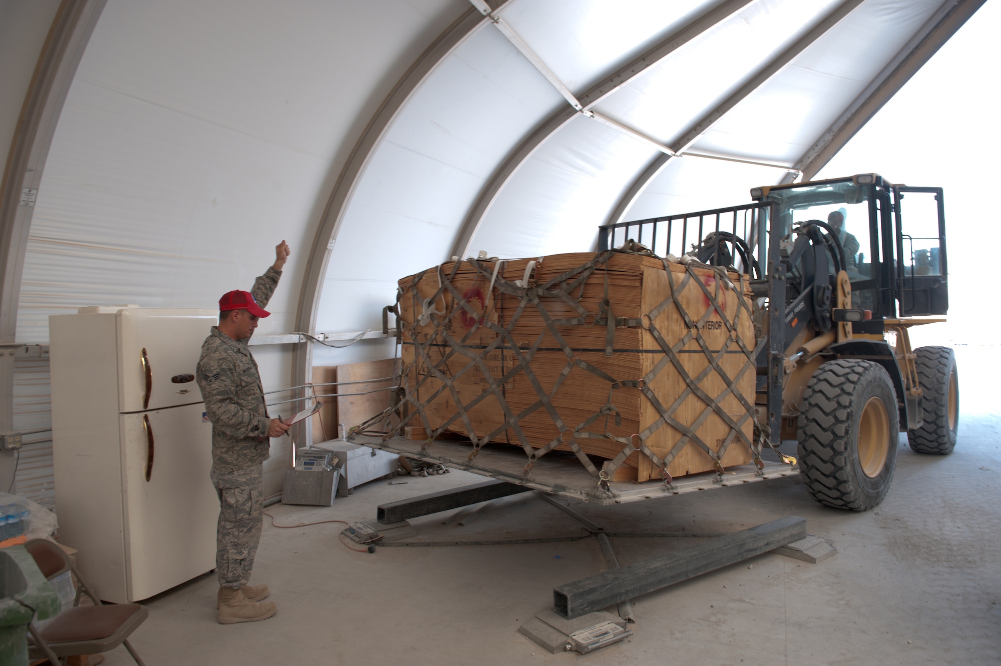 Left, Senior Airman Ryan McGraw, 1st Red Horse Group structural journeyman, guides a pallet of wood onto weight scales in order to have it shipped to Bagram Airfield, Sept. 15, in Southwest Asia. Airman McGraw, along with fellow members of the logistics and pallet build-up team, support all Red Horse operations downrange by obtaining and shipping required equipment. Airman McGraw is deployed from Dyess Air Force Base, Texas, in support of Operations Iraqi and Enduring Freedom. (U.S. Air Force Photo/Staff Sgt. Robert Barney)