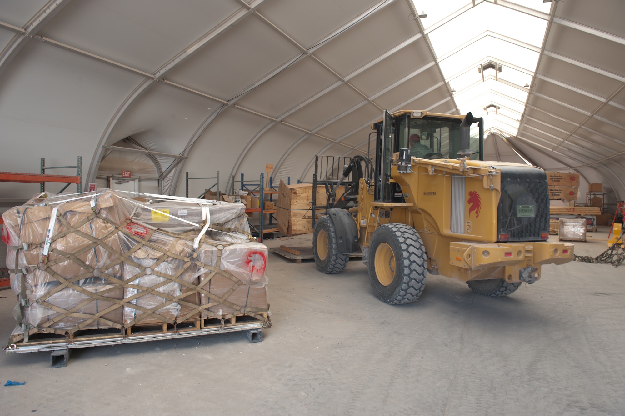 U.S. Air Force Staff Sgt. Dennis Urruchi, 1st Expeditionary RED HORSE Group electrical craftsman, lowers a stack of wood to be palletized and shipped to Bagram Airfield, Sept. 15, in Southwest Asia. Sergeant Urruchi, along with fellow servicemembers of the logistics and pallet build-up team, support all RED HORSE operations downrange by obtaining and shipping required equipment for mission success. Sergeant Urruchi is deployed from Peterson Air Force Base, Colo., in support of Operations Iraqi and Enduring Freedom. (U.S. Air Force Photo/Staff Sgt. Robert Barney/RELEASED)