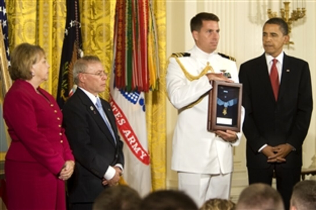 A Navy lieutenant commander holds the Medal of Honor that President Barack Obama posthumously awarded to Army Sgt. 1st. Class Jared C. Monti, as his parents, Paul and Janet Monti,  from Raynham, Mass., stand by in the East Room of the White House in Washington D.C., Sept. 17, 2009. "Jared Monti saw danger before him and he went out to meet it," Obama said in the ceremony.  