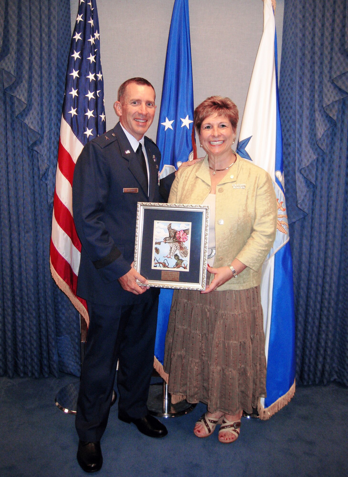 Brig. Gen. Brett and Marianne Williams show the picture of "The Falcon and the Rose" that was presented to them during a ceremony at the Pentagon Sept. 11, 2009, where they were honored with the 2009 General and Mrs. Jerome O'Malley Award.  Tradition says the falcon and rose are powerful and enduring symbols within the Air Force -- the unrivaled courage and effortless power of a falcon in flight are bound in harmony with the simple grace and unchallenged beauty of a single rose.  The O'Malley award is presented annually to the wing commander and spouse team who have best exhibited their own courage, power, grace and beauty in caring for Air Force families.  (Courtesy photo)