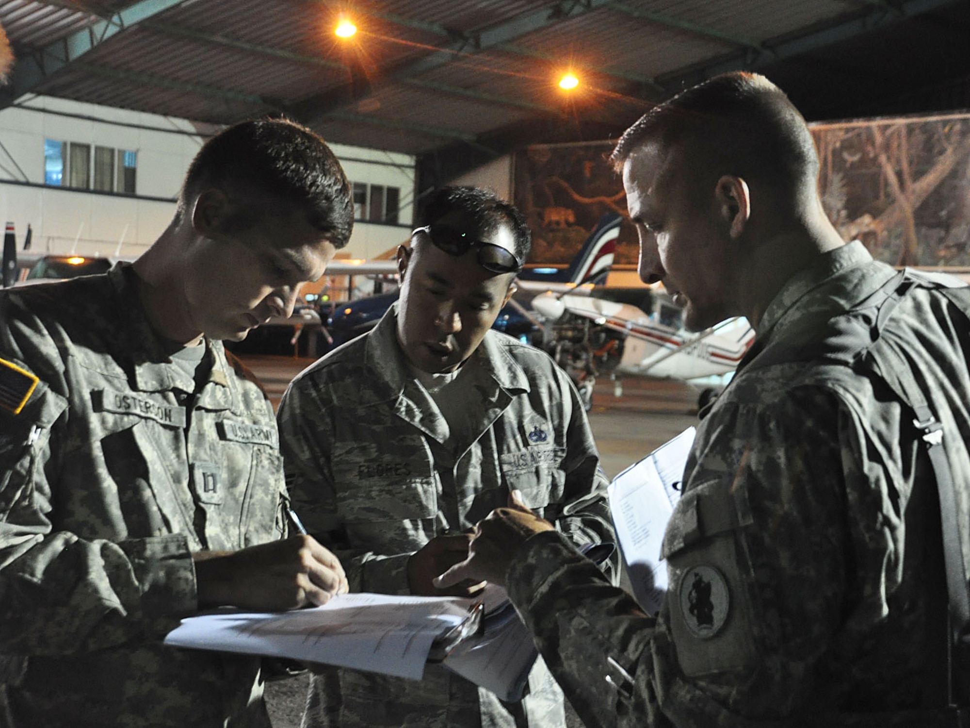 Just before dawn breaks at the Juan Santamaria International Airport in San Jose, Costa Rica, U.S. Army Capt. John Osterman, Air Force Tech. Sgt. Bill Flores, and Army Lt. Col. Curtis Anderson finalize the airlift plan for three Blackhawk helicopters supporting the Medical Readiness and Training Exercise in the remote Turrialba region of that Central American nation. (U.S. Air Force photo/Tech. Sgt. Mike Hammond)