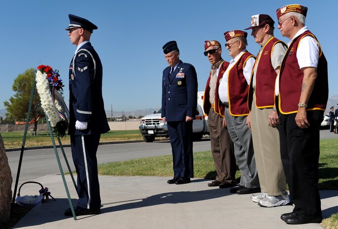 NELLIS AIR FORCE BASE, Nev. -- Airman 1st Class Sharif Abouomar, a member from the Nellis Honor Guard team, honors the Prisoners of War/Missing in Action Recognition Day memorial wreath along with Brig. Gen. Kevin McLaughlin, United States Air Force Warfare Center vice commander, and veterans from the 7-11 Chapter of the American Ex-Prisoners of War, here, Sept. 18. The ceremony is held annually for surviving veterans and those that never returned from combat. (U.S. Air Force photo by Airman 1st Class Brett Clashman)
