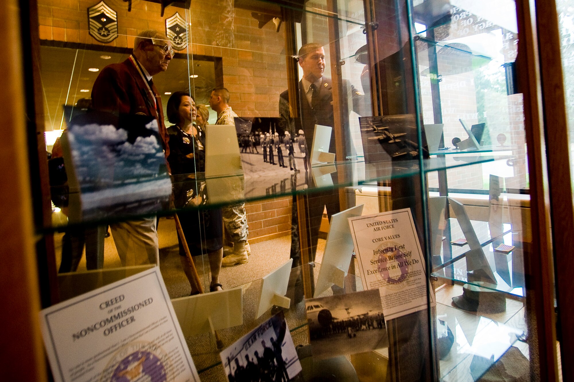 Senior Airman Brock Merriman, 62nd Maintenance Operations Squadron, right, points to Air Force memorabilia while providing former POW Wallace Tharp and his wife Anh with a tour of McChord's enlisted heritage room as part of the 62nd Airlift Wing's annual POW/MIA recognition luncheon Sept 17. (U.S. Air Force Photo by Abner Guzman)

