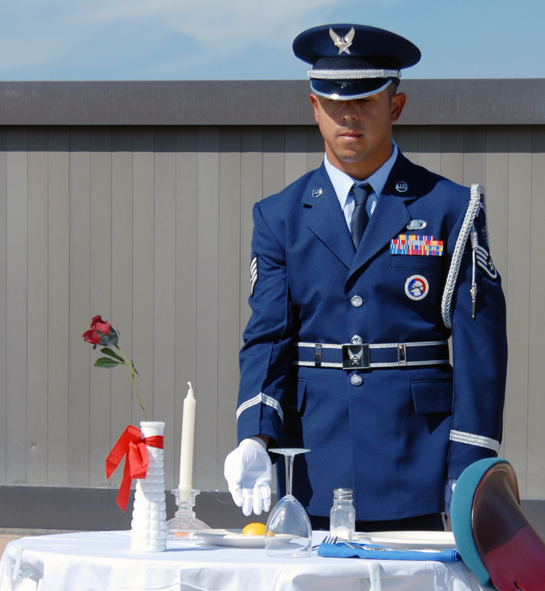 Staff Sgt. Adrian Ortiz, from the Air Reserve Personnel Center Honor Guard here, sets the table dedicated to prisoners of war and missing in action during the POW/MIA Commemoration Day Vigil on Sept. 17. Throughout the night, pairs of people took 30-minute shifts reading the names of nearly 10,000 people missing or taken prisoner from the Cold War through current operations. (U.S. Air Force photo/Dwayne Beuthel)