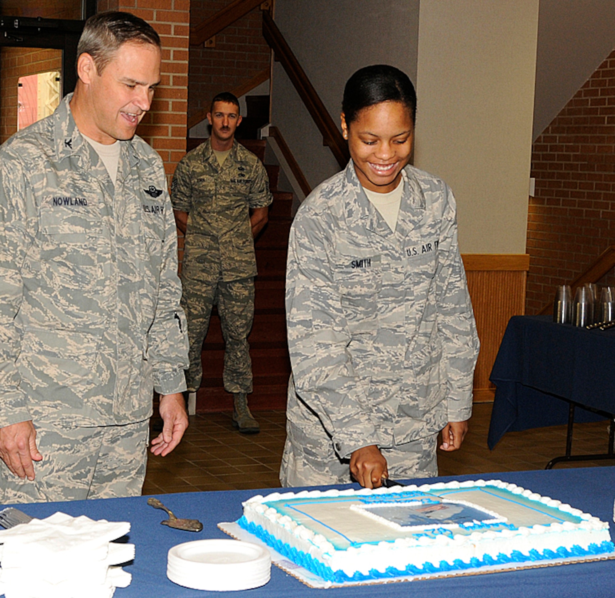 With guidance from Col. Chris Nowland, left, Airman Basic Shakon Smith cuts the cake Sept. 18 to celebrate the U.S. Air Force’s 62nd birthday during a ceremony in the atrium of Bldg. 500 at Vance AFB, Okla. Colonel Nowland is the 71st Flying Training Wing commander. Airman Smith, the newest member of the Air Force at Vance, enlisted March 29 this year. She is from Cordele, Ga. (U.S. Air Force photo/ Angie Roche)
