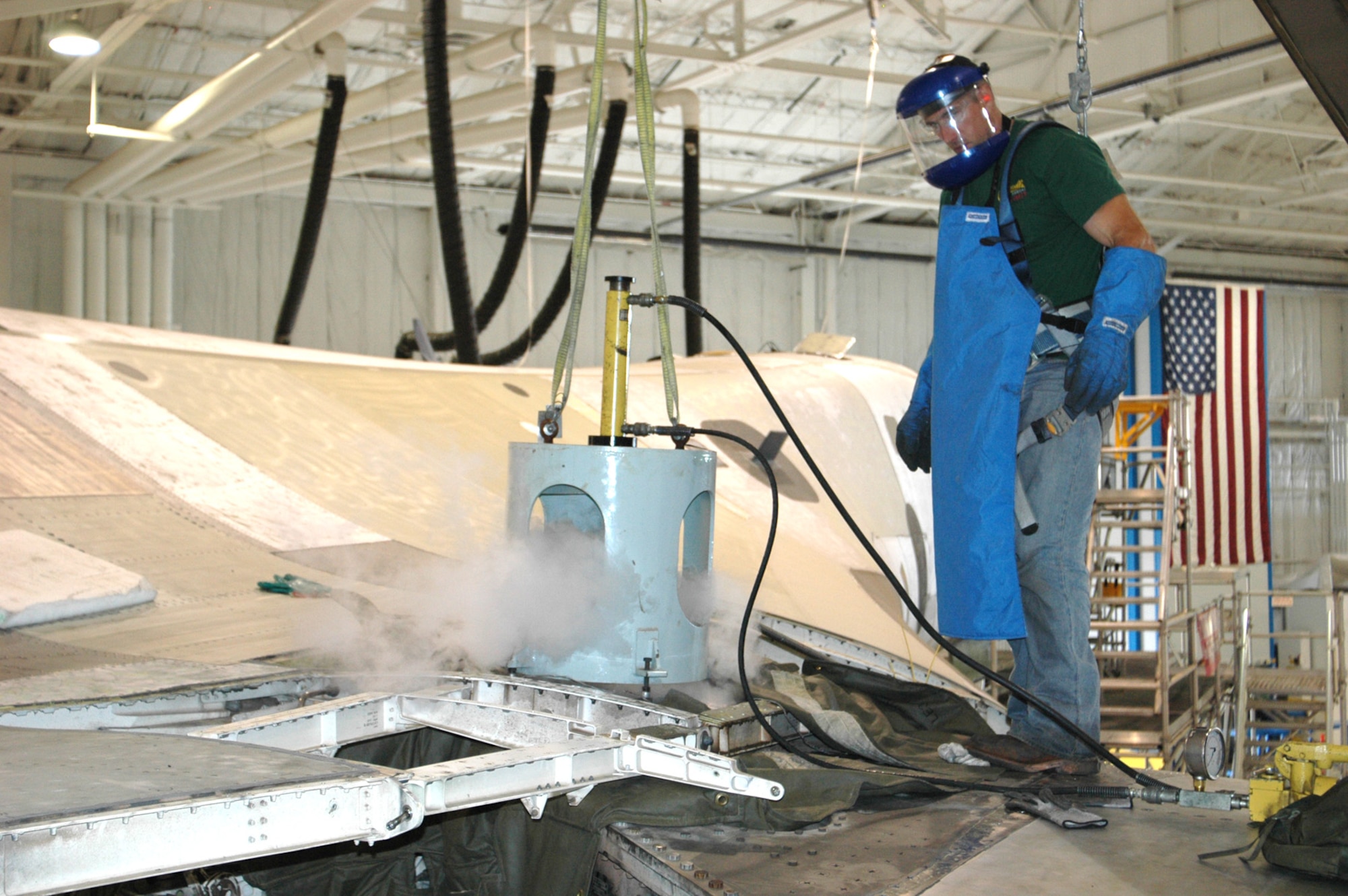 Randy Orr, 565th Aircraft Maintenance Squadron,  injects liquid nitrogen into the pivot pin on a B-1 Bomber at Tinker for maintenance. The liquid nitrogen supercools the pin, which then shrinks, becoming easier to remove from the aircraft. The pin is what allows the aircraft’s wings to pivot when in flight. With only thousandths of a micrometer of space to spare, the prototype process requires much precision. (Air Force photo by Howdy Stout)