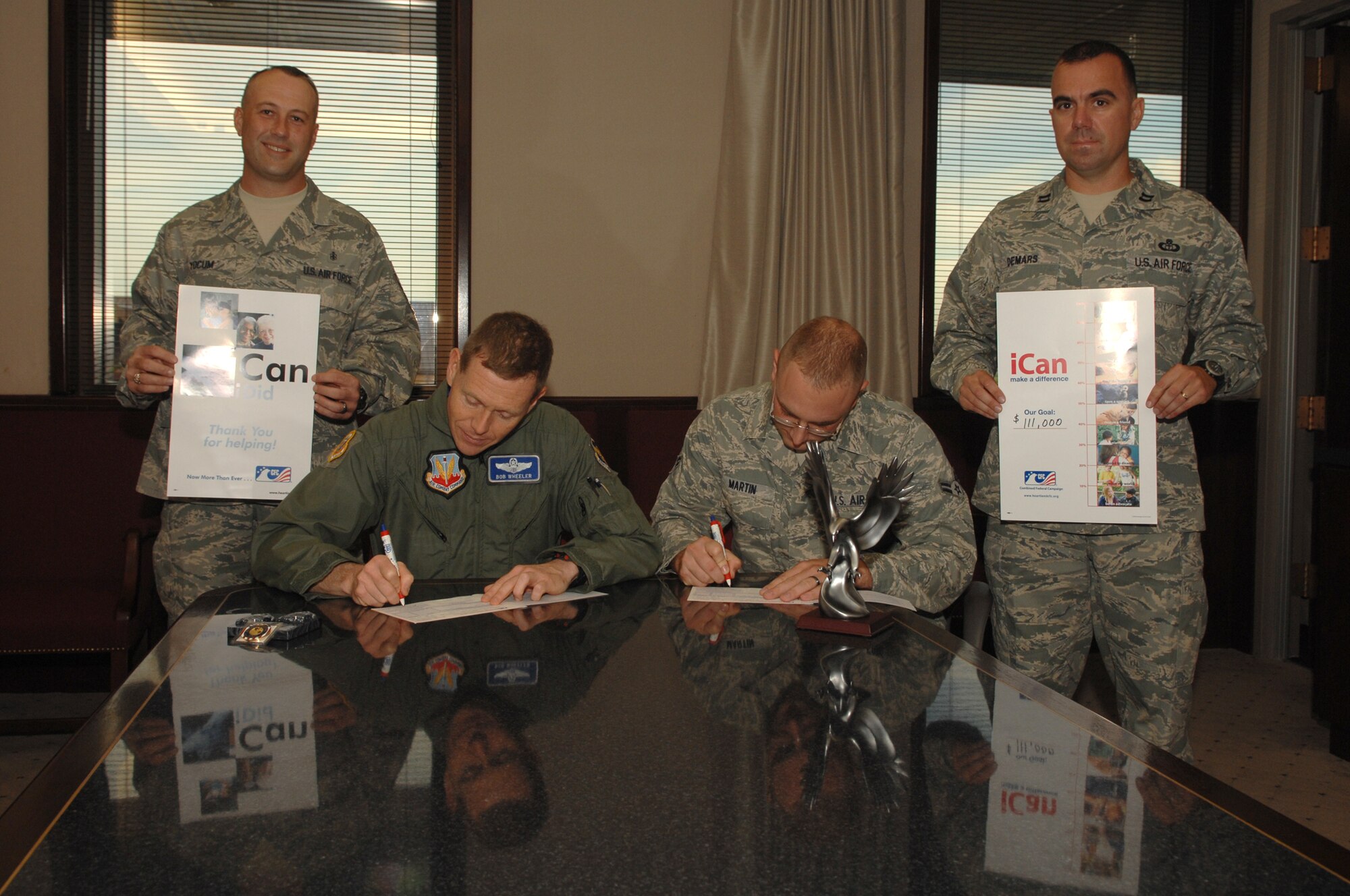 WHITEMAN AIR FORCE BASE, Mo. -- Whiteman's Combined Federal Campaign  representatives, Capt. Glen DeMars, 509th Operations Support Squadron, and Master Sgt Brit Yocum, 509th Medical Support Squadron, watch as Brig. Gen. Robert Wheeler, 509th Bomb Wing commander, and Airman 1st Class Loren Martin, 509th Maintenance Squadron, give the first donations for this year’s Combined Federal Campaign. The campaign kicked off September 30th and will run through November 12. A weekly update of the base CFC goal progress will be featured in the Warrior. (U.S. Air Force photo/Senior Airman Jessica Snow)
