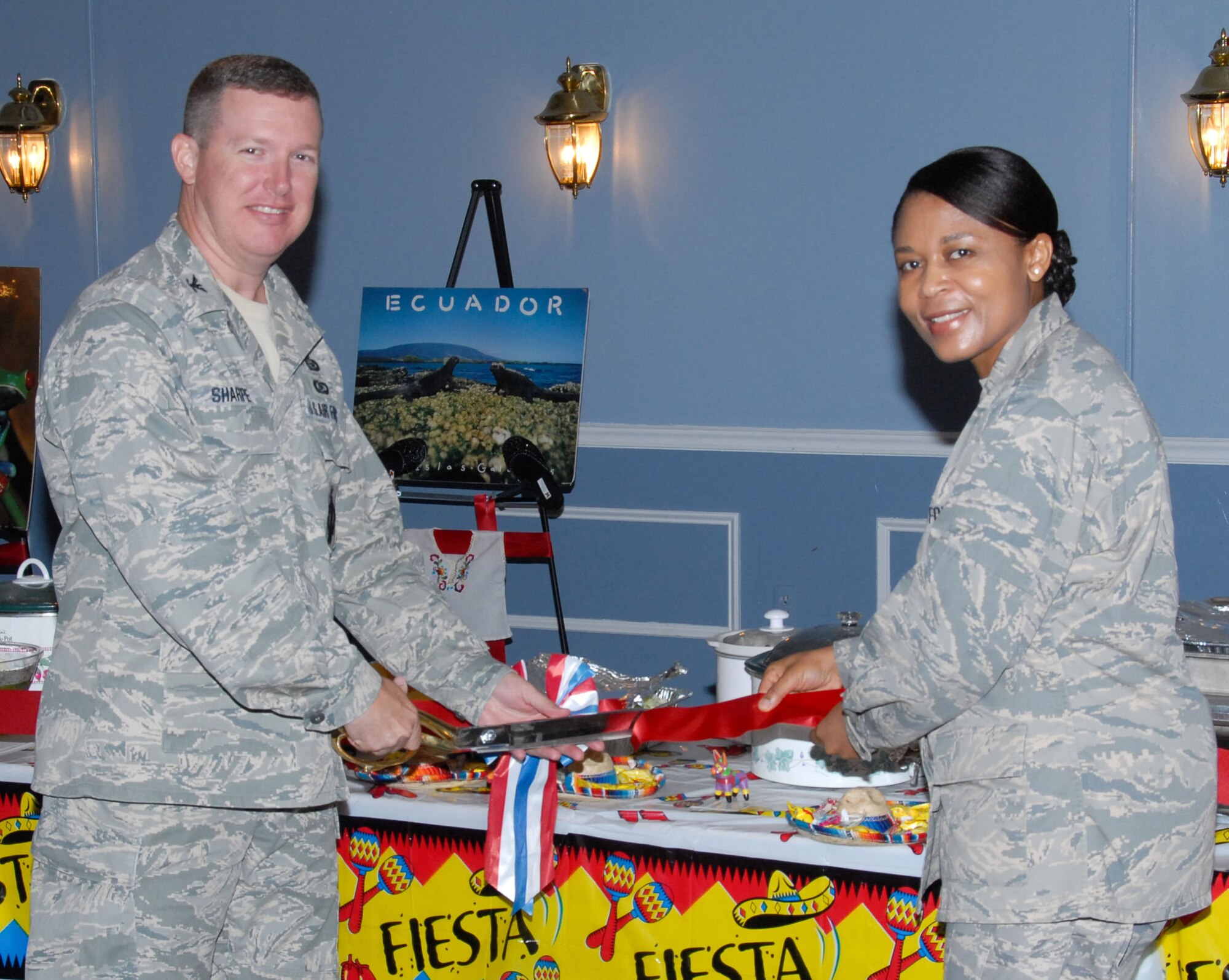 Col. Christopher Sharpe, the 42nd Air Base Wing vice commander, and Maj. Claudine Wega of the 42nd Medical Group, cut a ceremonial ribbon in front of a variety of home-cooked delicacies at the Hispanic Heritage Month opening ceremony Tuesday at the Maxwell Event Center. (U.S. Air Force photo/Bud Hancock) 
