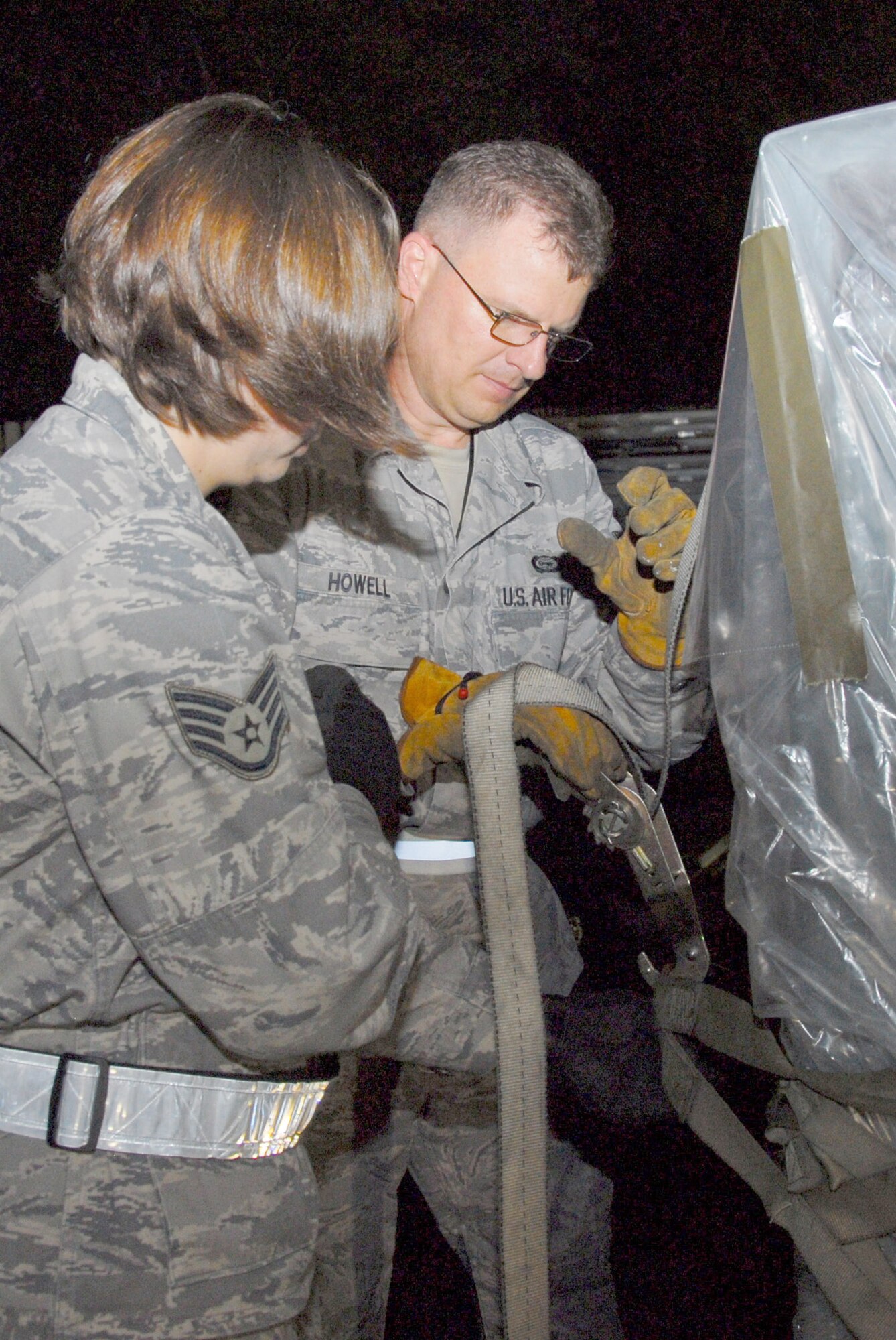 Nightime made no difference as aircraft loading continued, a "K-loader" is maneuvered inside a C-5, 908th mobility bags are pulled from storage and prepared for loading, a portable heater and electric generator are positioned and 908th members ensure a cargo pallet is securely fastened. (U.S. Air Force photo/Jamie Pitcher)
