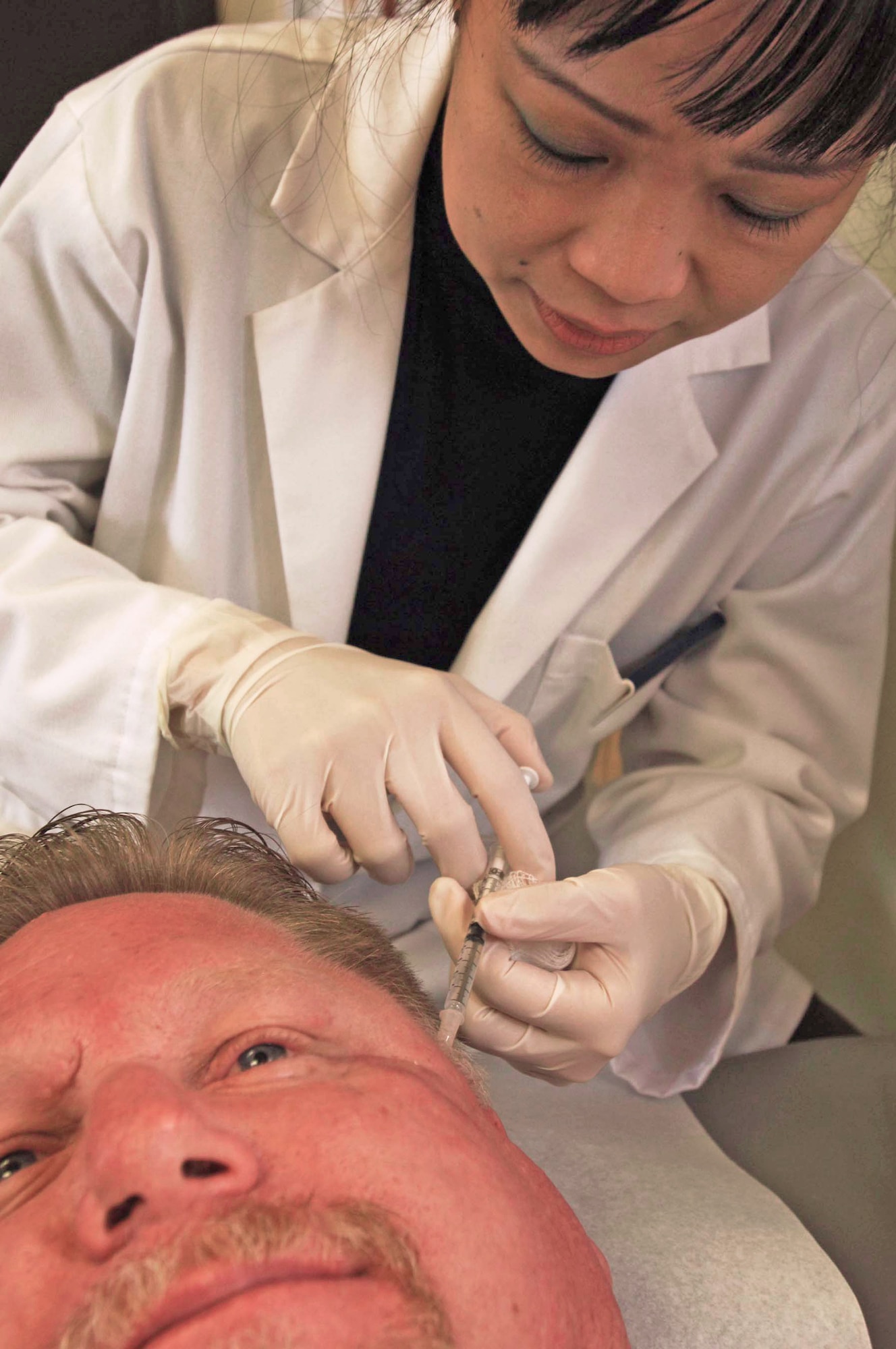 Maj. (Dr.) Maria Alvarez injects Robert O'Reilly with botulinum toxin Sept. 9, 2009, at Lackland Air Force Base, Texas. Doctor Alvarez, a Wilford Hall neurologist, is leading a case study to improve treatment of tramatic brain injury patients with chronic headaches. (U.S. Air Force photo/Senior Airman Amber Bressler)