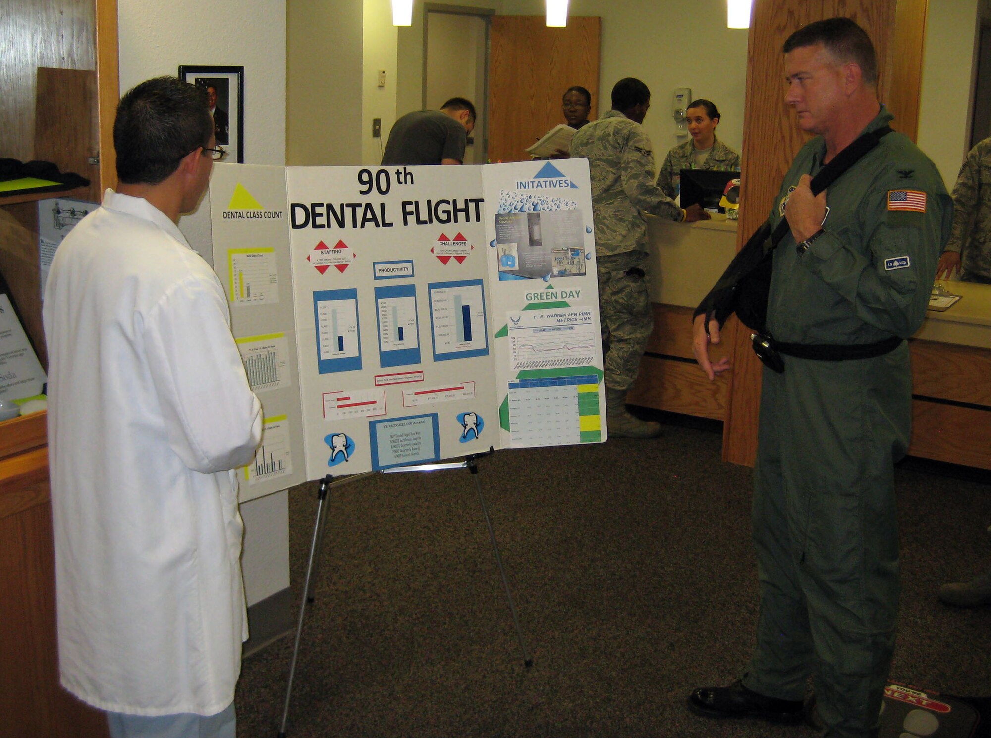 Col. Greg Tims, 90th Missile Wing commander looks over a dental flight poster board with Senior Airman Tommy Vinh, 90th Medical Operations Squadron, during his 90th Medical Group tour Sept. 10