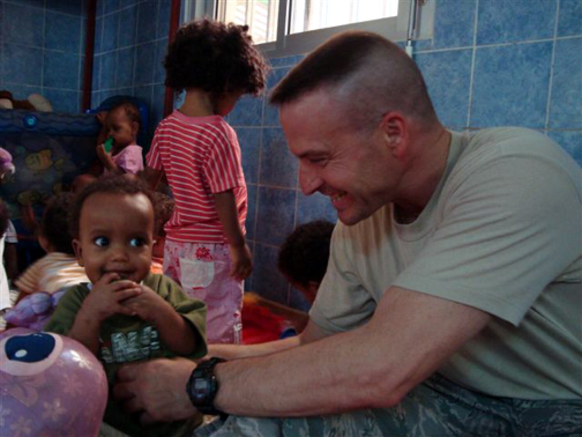 Master Sgt. Andrew Henne, who started the donation drive with United Communities, plays with children in an orphanage in Djibouti, Africa, while deployed there in June. UC will continuously accept donations to send to children in schools and orphanages in Djibouti, where many McGuire Airmen are currently deployed. (U.S. Air Force courtesy photo) 