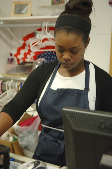 Regan Porter, B-One Yard manager, rings up a sale at the B-One Yard thrift and consignment shop here, Sept. 9. The shop is staffed by volunteers and stocked with donations from base personnel. (U.S. Air Force photo/Airman 1st Class Jarad Denton)