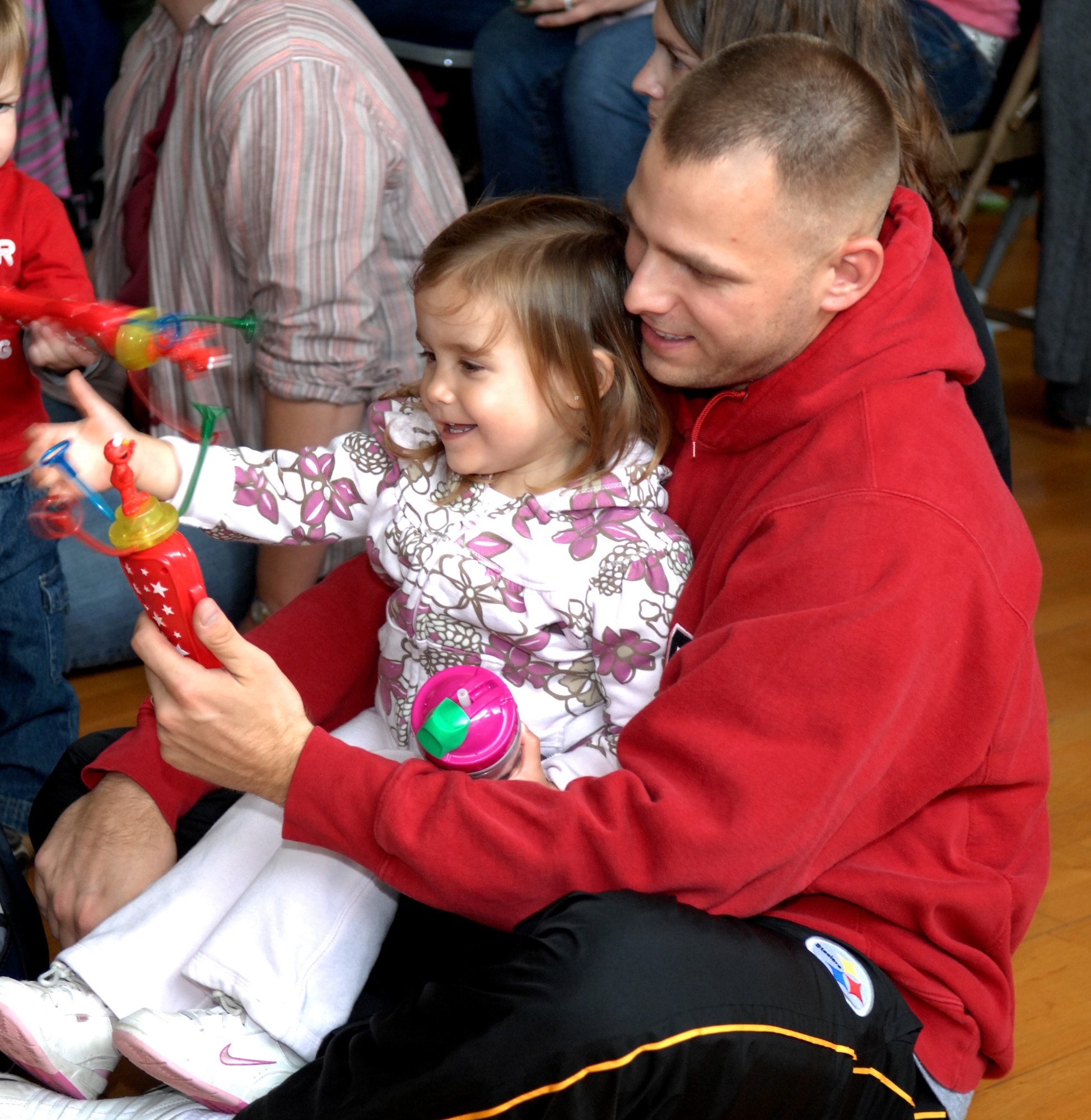 SPANGDAHLEM AIR BASE, Germany – Kalea Merski and her father Staff Sgt. Greg Merski, Civil Engineering Squadron, watch the Sesame Street Experience on tour at the Bitburg Annex gym Sept. 16. The travelling USO-sponsored tour is free and dedicated to helping military families deal with the emotional stresses that come with being a military parent or child of a deployed servicemember. Bitburg Annex was the fourth stop on the group’s European tour with 16 bases remaining.  (U.S. Air Force photo/Airman 1st Class Staci Miller)