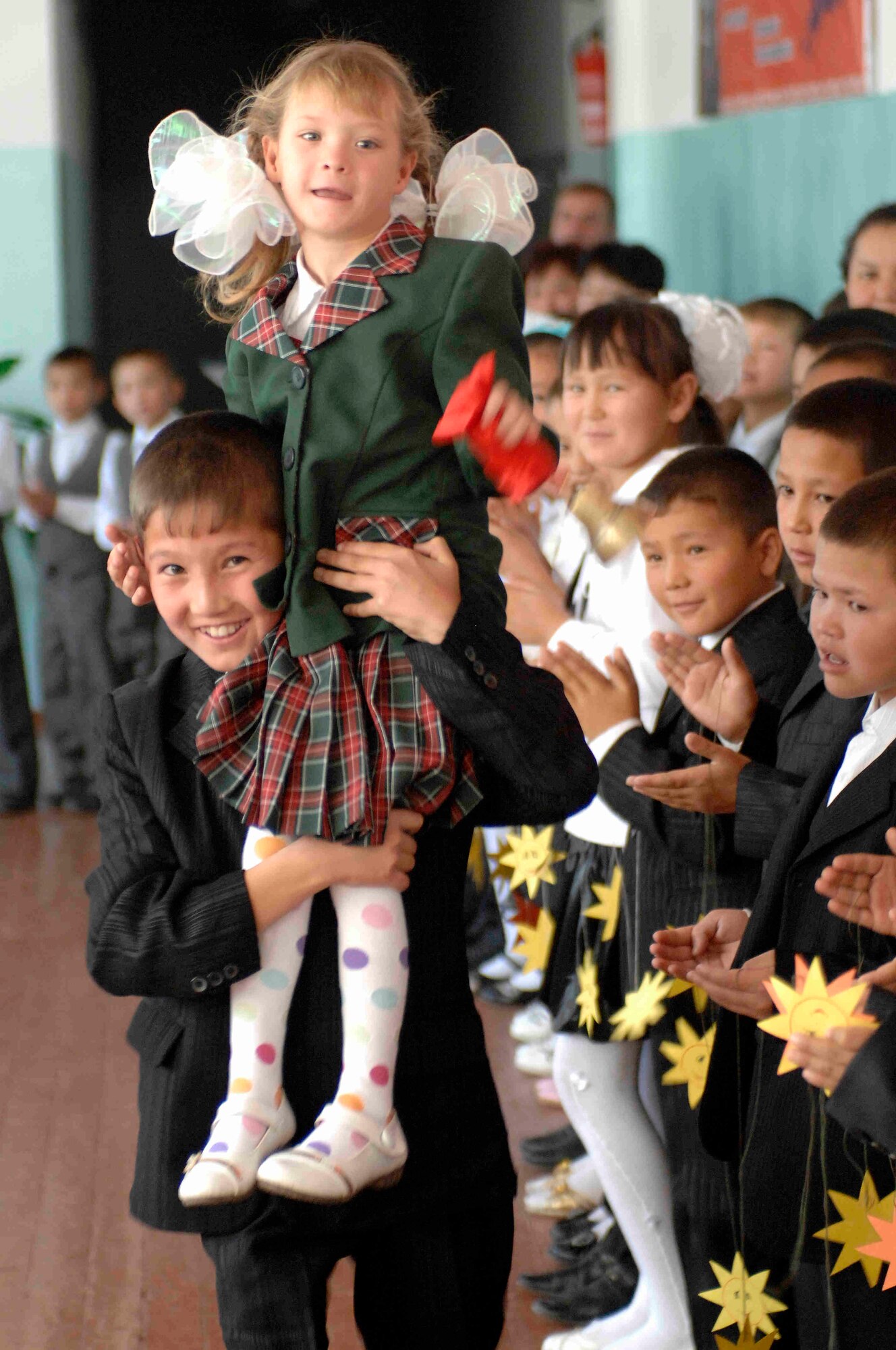 NIZHANCHUISK VILLAGE, Kyrgyzstan -- The youngest student rings a bell while carried by another student, at the Nizhanchuisk School, marking the start of the new school year, Sept. 8, 2009. Airmen from the Transit Center at Manas were invited to share in the ceremony of music and tradition marking the new school year. (U.S. Air Force photo/Senior Master Sgt. Andrew Lynch)