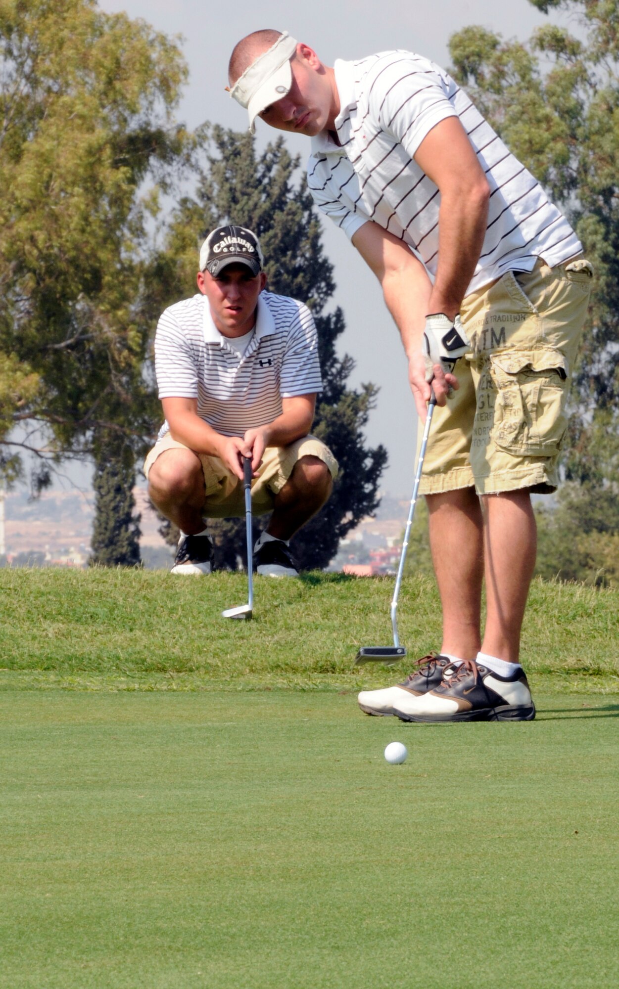 Shawn Archibald, a 39th Maintenance Squadron aerospace ground equipment mechanic, putts out on the first hole of Hodja Lakes Golf Course while his teammate, Paul Schone, also an AGE mechanic, looks on during the 2009 Intramural Golf Championship Wednesday, Sept. 16, 2009, at Incirlik Air Base, Turkey.  Archibald and the rest of his 39th MXS team won the championship after defeating the team representing the 39th Force Support Squadron.  The win earned the 39th MXS points toward the Commander’s Trophy which is given to the squadron with the most overall points earned in intramural sports at the end of the year.  (U.S. Air Force photo/Staff Sgt. Raymond Hoy)