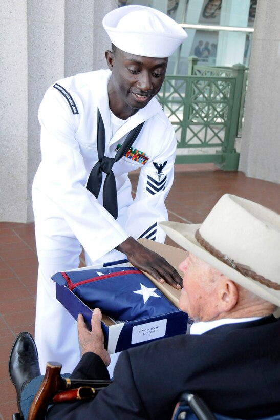 John Finn, Medal of Honor recipient, receives a flag from his military escort, shortly before the opening ceremony of the Medal of Honor Convention at Soldier Field, Chicago, Sept 15, 2009.  The flag had been previously flown over Soldier Field on the anniversary of the date Finn received the Medal of Honor.