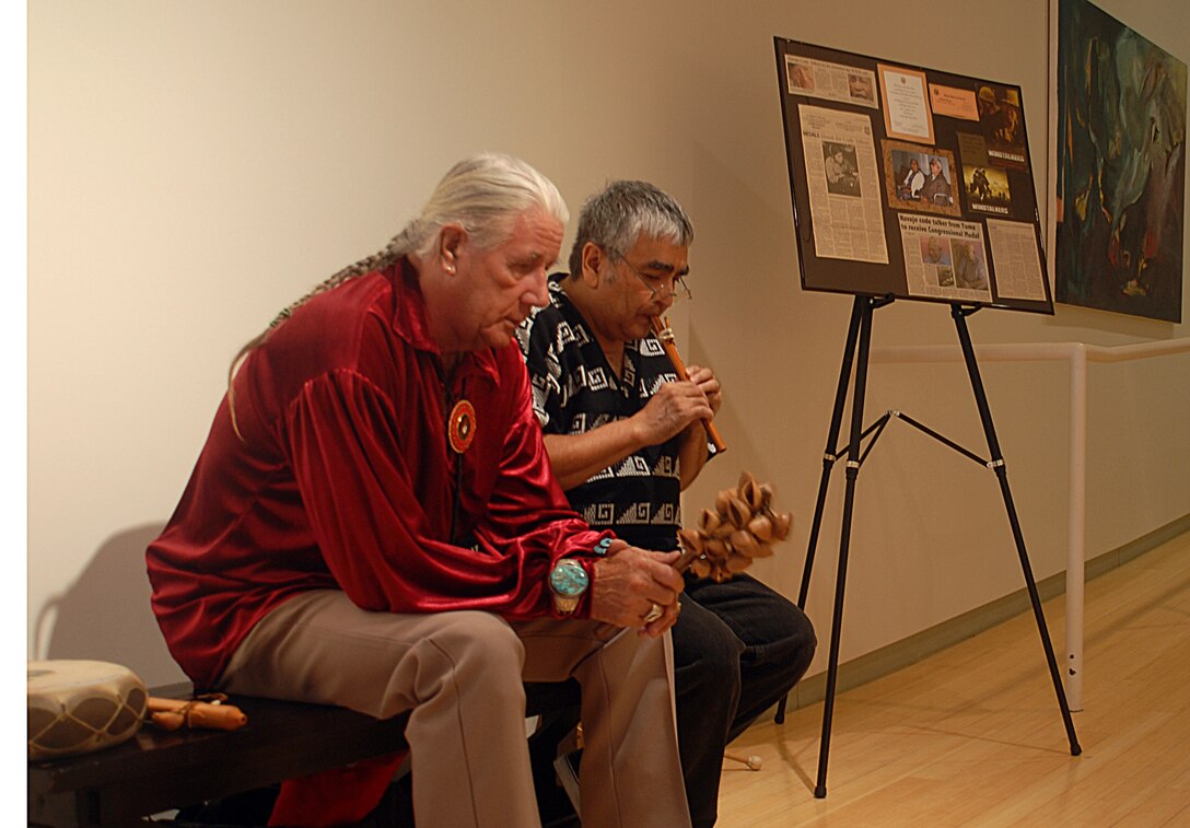 Retired Gunnery Sgt. Chuck Bekay Bauer, left, and Larry Yanez, a local musician, play Navajo music next to a display honoring Navajo code talkers of World War II at the Yuma Art Center in Yuma, Ariz., Sept. 18, 2009. The center will display a photographic exhibit honoring the Navajo code talkers until Oct. 3, 2009. The exhibit is sponsored by the Circle of Light Navajo Education Project and includes more than 33 photographs that detail the history of the code talkers and their many accomplishments.
