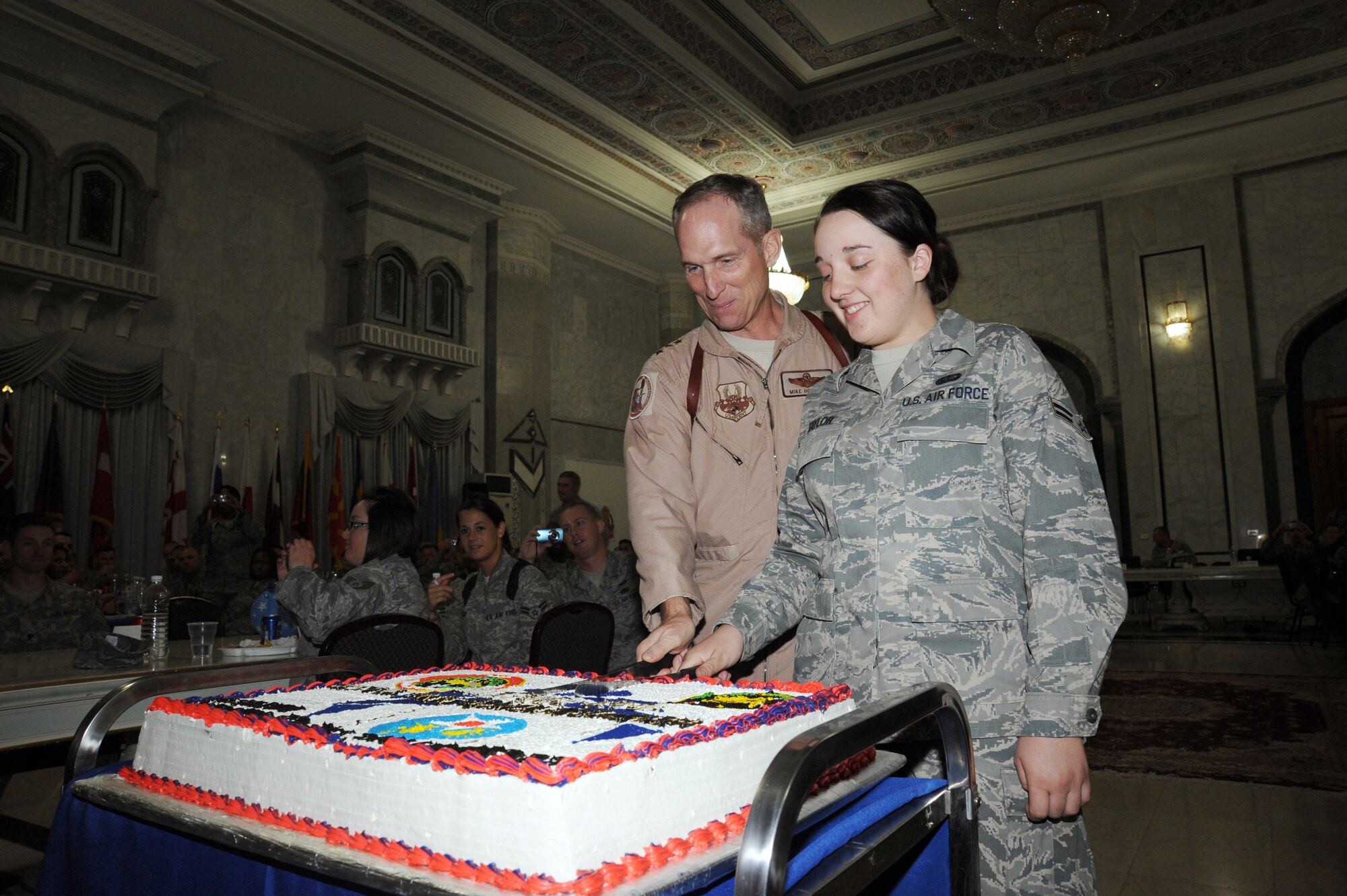 CAMP VICTORY, Iraq -- Airman 1st Class Liana Taylor (right), 447th Expeditionary Force Support Squadron services technician, helps Lt. Gen. Mike Hostage, U.S. Air Forces Central Command commander, cut the Air Force birthday cake at Al Faw Palace here Sept. 18, 2009. As is tradition, the highest and lowest ranking Airmen in attendance have the privilege of cutting the cake. More than 200 servicemembers attended the ceremony celebrating the Air Force's 62nd birthday where Maj. Gen. Joseph Reynes Jr., Air Component Coordination Element director, served as the keynote speaker for the evening. Airman Taylor is deployed from Barksdale Air Force Base, La., and hails from Harwich, Mass. (U.S. Air Force photo/Tech. Sgt. Johnny L. Saldivar)