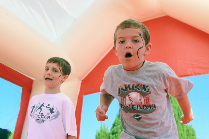 Patrick Grogan (left) and Jack Reed (right) demonstrate their jumping skills inside an air bounce during the Boys and Girls Club Day located on the parade deck in front of Building 1 on Sept. 19. Grogan and Reed met each other in the air bounce after realizing that they had matching snakes painted on their faces. Children attending the event had the opportunity to watch live performances, eat cotton candy and make colorful bracelets.