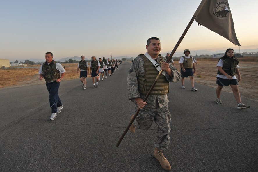 Tech. Sgt. Juan Valdez carries the guidon to the front of the formation during the 4th Combat Camera Squadron’s 3.5 mile march in August. The march was a way to recognize the squadron’s nine Airmen who are about to deploy. The unit plans to continue this tradition in the future. (U.S. Air Force photo by Staff Sgt. Efren Lopez)