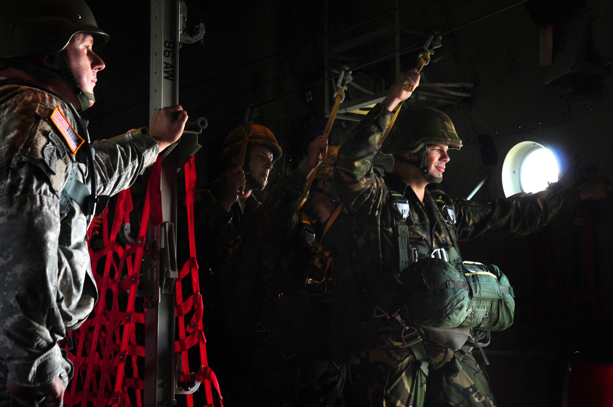 A U.S. Army Airborne jump master looks on as German paratroopers prepare to jump from a U.S. Air Force C-130J from Ramstein AB, Germany as they jump over the Dutch town of Arnhem, in commemoration of the 65th anniversary of Operation Market Garden.  The jump included over 1,000 men and women from six countries. (U.S. Air Force photo by Staff. Sgt. Jocelyn Rich) 