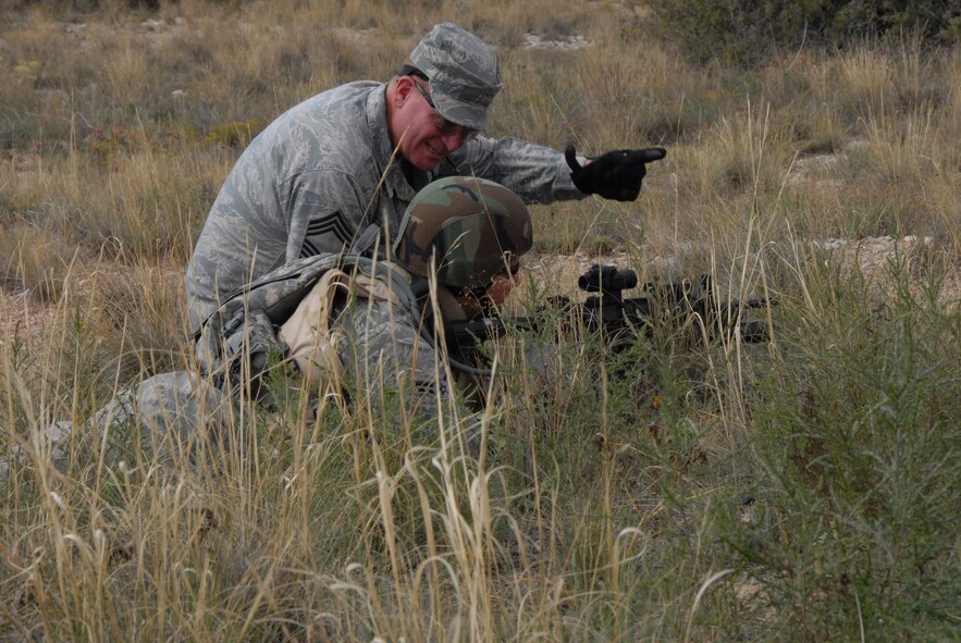 Chief Master Sgt. John Criswell of the 140th Security Forces Squadron instructs a young Airman on what to look for when watching an area of responsibility during a live fire training exercise Sept. 12, 2009 at Fort Carson, Colo. The Airman is attempting to see over the tall weeds that obstruct his view. During the training, 140th SFS cadre members passed on their knowledge and experience to guide the younger troops in order to make the training more efficient and practical for real-world scenarios. (Official U.S. Air Force photo by Staff Sgt. Armando Argiz, Colorado Air National Guard/Released)