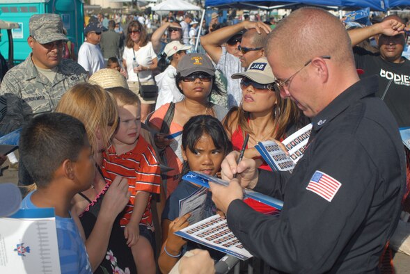 HICKAM AIR FORCE BASE, Hawaii --Staff Sgt. Steven Shoemake, U.S. Air Force Air Demonstration Squadron dedicated crew chief, signs autographs for Thunderbird fans during the Open House, "Wings over the Pacific," here, Sep. 19. The Open House featured live band performances, static displays and The Thunderbirds demonstrated the capabilities of the F-16 Fighting Falcon when they preformed combat maneuvers at the air show. (U.S. Air Force photo/Senior Airman Gustavo Gonzalez)