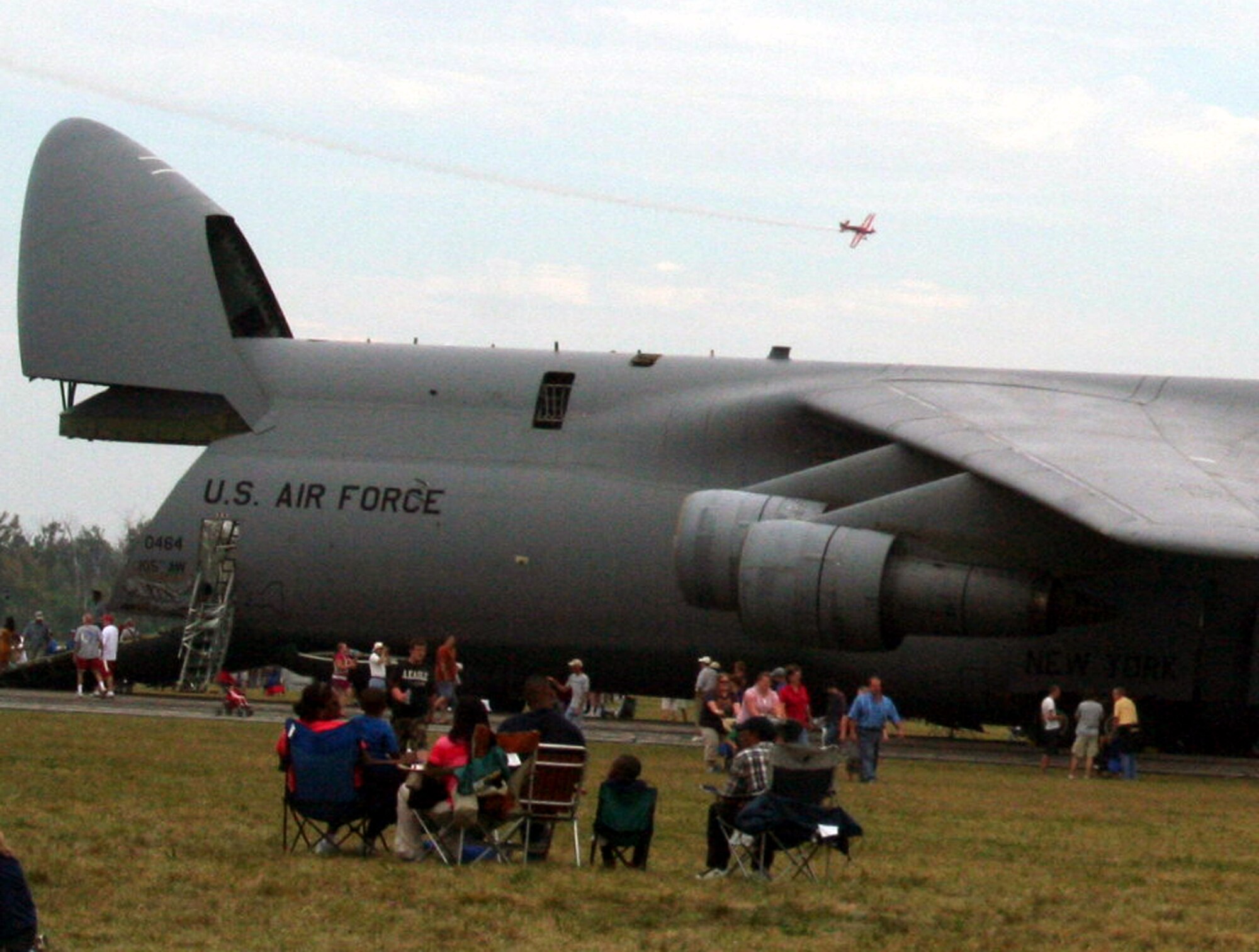 A propeller-driven aircraft performs and aeriel maneuver while show attendees look at a C-5 Galaxy during the 2009 Scott Air Force Base Airshow on Sept. 19, 2009, at Scott AFB, Ill.  The airshow drew tens of thousands of people and featured a wide variety of aircraft on static display and in aerial performances.  (U.S. Air Force Photo/Tech. Sgt. Scott T. Sturkol)