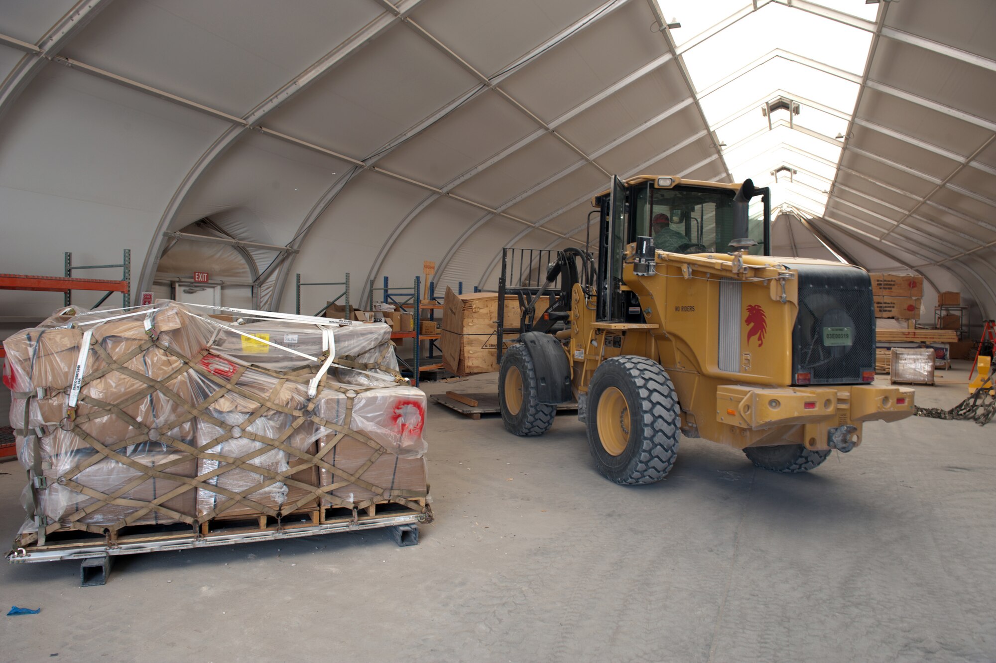 Staff Sgt. Dennis Urruchi lowers a stack of wood to be palletized and shipped Sept. 15, 2009, at an air base in Southwest Asia. Sergeant Urruchi is a 1st Expeditionary RED HORSE Group electrical craftsman. He along with fellow servicemembers of the logistics and pallet build-up team, support all RED HORSE operations downrange by obtaining and shipping required equipment for mission success. Sergeant Urruchi is deployed from Peterson Air Force Base, Colo. (U.S. Air Force photo/Staff Sgt. Robert Barney) 