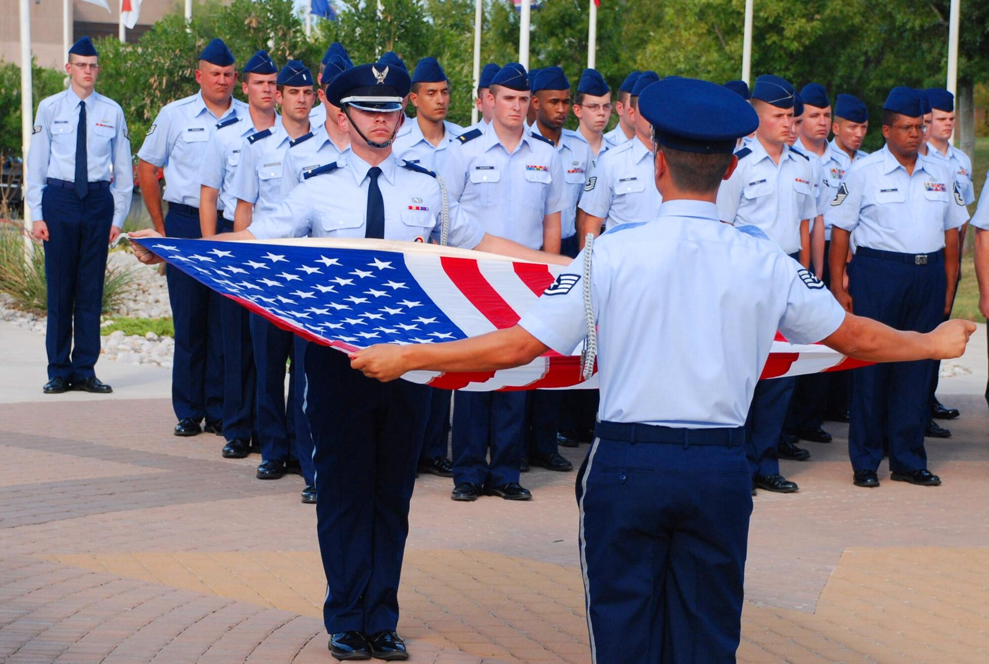 LAUGHLIN AIR FORCE BASE, Texas – Members of the Laughlin Honor Guard perform a flag-folding ceremony as a formation of Airmen commanded by Senior Master Sgt. John Maldonado, 47th Installation Support Squadron, looks on during the POW/MIA Remembrance ceremony here Sept. 18. The ceremony was held in observance of National POW/MIA Remembrance Day, which is held the third Friday in September as a way to remember former American prisoners of war and those still missing in action. (U.S. Air Force photo by Airman 1st Class Blake Mize)