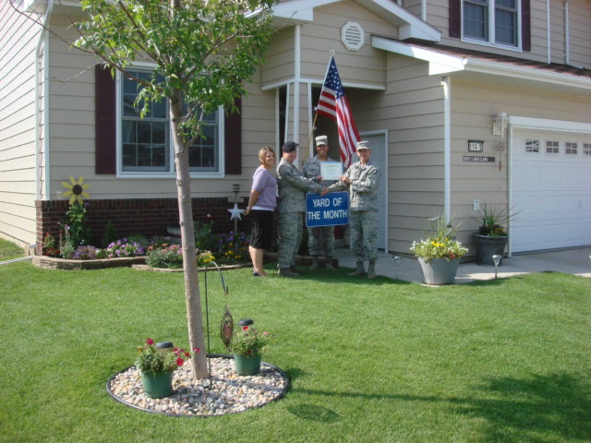 MINOT AIR FORCE BASE, N.D. -- Staff Sgt. William Clark, 5th Security Forces Squadron, and his wife, Ashley, pose for a photo after winning yard of the month for the month of September. Col. James Gallagher, 5th Mission Support Group commander, and Chief Master Sgt. John Hemmy, 5th MSG superintendent, presented the award to the Clarks. The Clarks meticulously maintained residence earned them a $100.00 saving bond from the Minot Chapter of the Air Force Association, a $10.00 gift card from AAFES, and $15.00 in Darby Dollars to spend in 5th Force Support Squadron facilities. (courtesy photo)