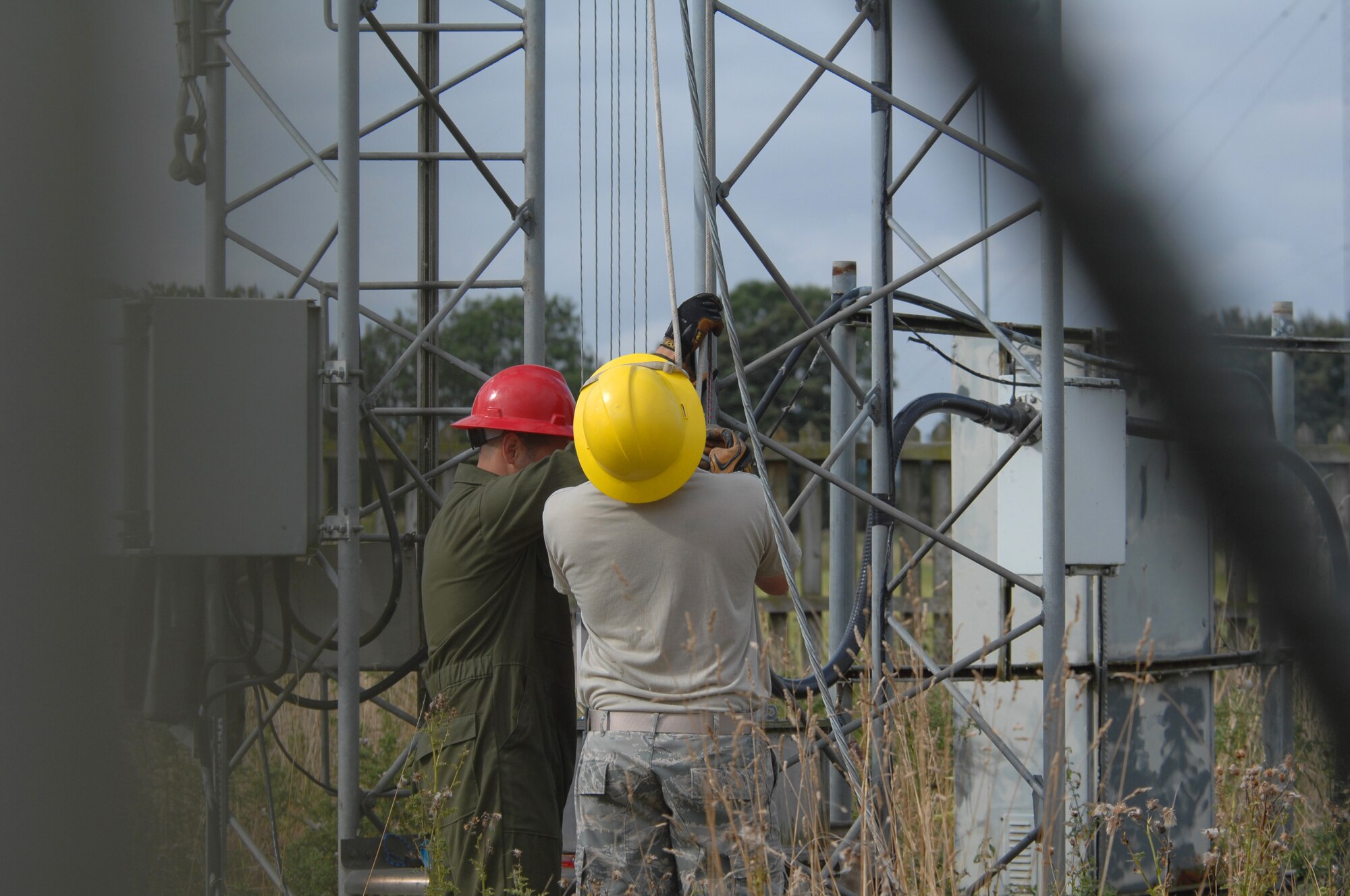 U.S. Air Force Staff Sgt. Scot Craig and Carlos Salinas, 1st Communications Maintenance Squadron, hold tension to a rope used to lower a guywire which holds tenison through tie-down points to a radio tower. They are members of the Cable and Antenna Theater Maintenance Team who travel routinely throughout Europe maintaining the communications capability force across the Atlantic. (U.S. Air Force photo by Tech. Sgt. Michael Voss)