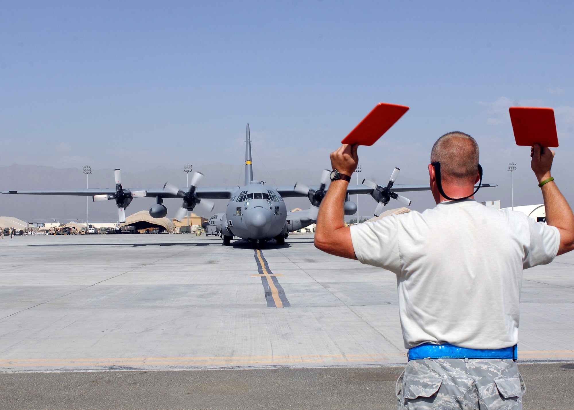 BAGRAM AIRFIELD, Afghanistan -- Senior Airman David Eastburn, 455th Expeditionary Aircraft Maintenance Squadron, marshals a C-130 into a parking spot here, Sept. 21, 2009.  The C-130's do everything from transporting cargo to transporting personnel; this particular C-130 is from Alaska.   Airman Eastburn is deployed from Delaware Air National Guard/s 166th Air Wing, and hails from Middletown, Del.  (U.S. Air Force photo/Senior Airman Felicia Juenke)