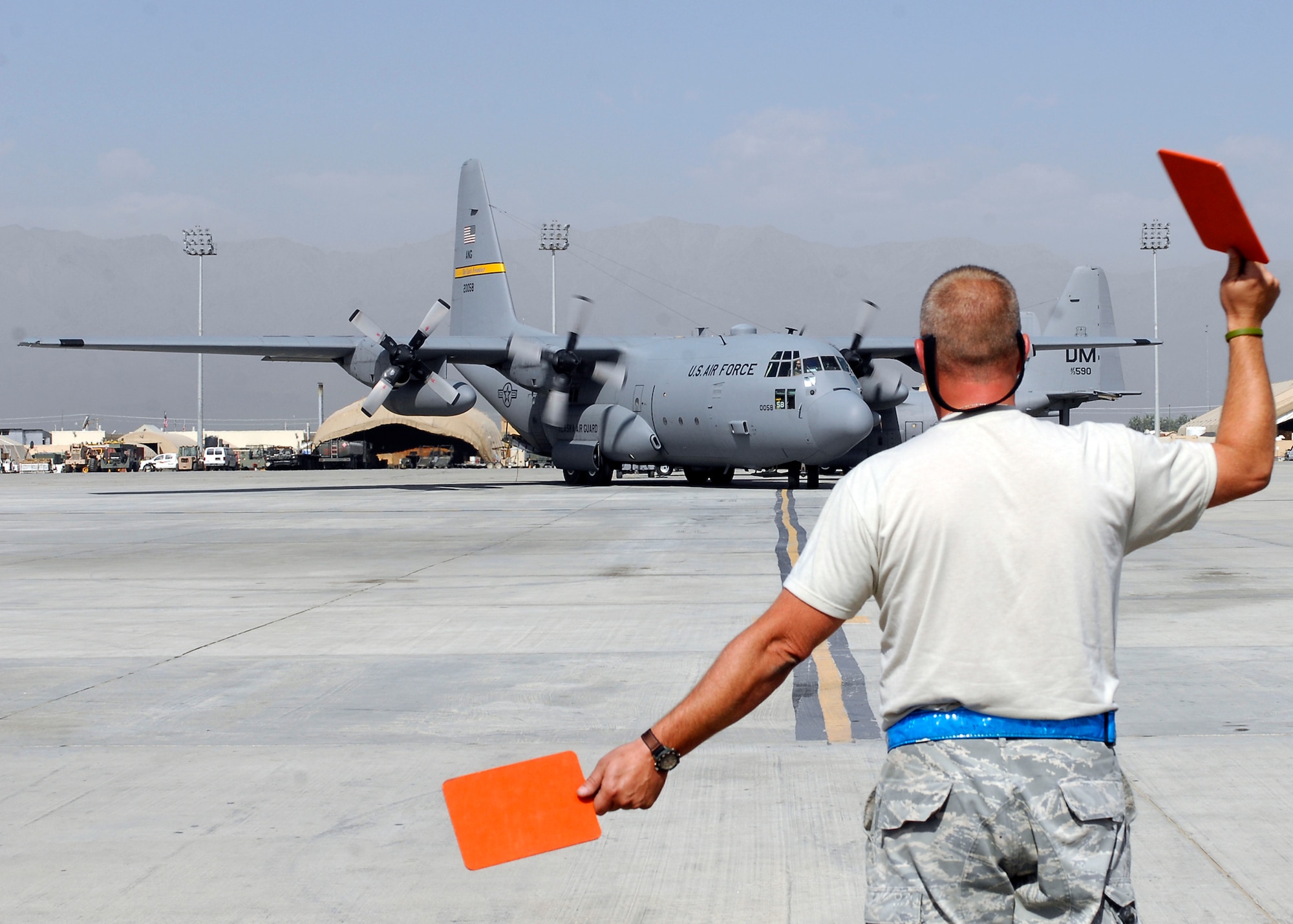 BAGRAM AIRFIELD, Afghanistan -- Senior Airman David Eastburn, 455th Expeditionary Aircraft Maintenance Squadron, uses directional-paddles to marshal in a C-130 here, Sept. 21, 2009.  This is done so the pilot knows when to turn while parks the aircraft on the busy flightline.  The C-130's do everything from transporting cargo to transporting personnel; this C-130 is from the 176th Airlift Wing in Anchorage, Alaska.  Airman Eastburn is deployed from Delaware Air National Guard's 166th Air Wing, and hails from Middletown, Del.  (U.S. Air Force photo/Senior Airman Felicia Juenke)