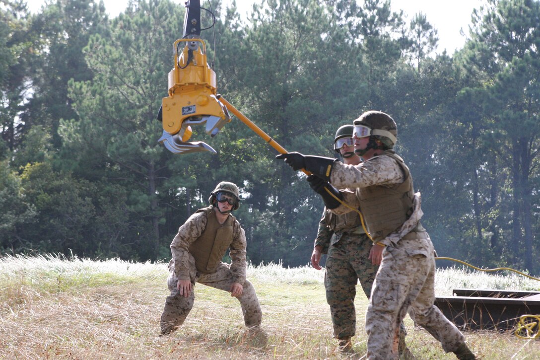 A Logistic Operations School Marine grounds the hook attached to the helicopter to stop the 250 volts from running through, during helicopter support team operations at Landing Zone Kite, Sept. 24