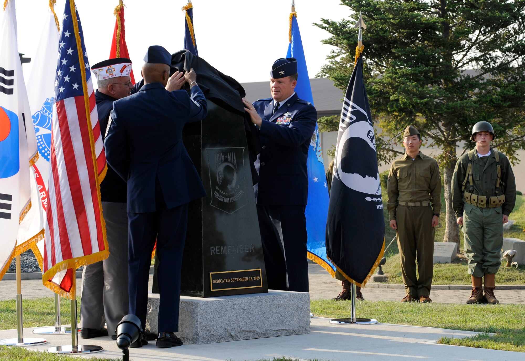 Col. Mark Mattison, right, Chief Master Sgt. Michael Williams, center, and Larry Lyons unveil a POW/MIA remembrance statue during a dedication ceremony in front of the base theater Sept. 18.  The ceremony honored those who sacrificed so much for their country. Colonel Mattison is the 51st Fighter Wing vice commander, Chief Williams is the 51st Fighter Wing command chief and Mr. Lyons is the former the former Veterans of Foreign Wars Department of the Pacific commander.  (U.S. Air Force photo/Staff Sgt. Brian Ferguson)