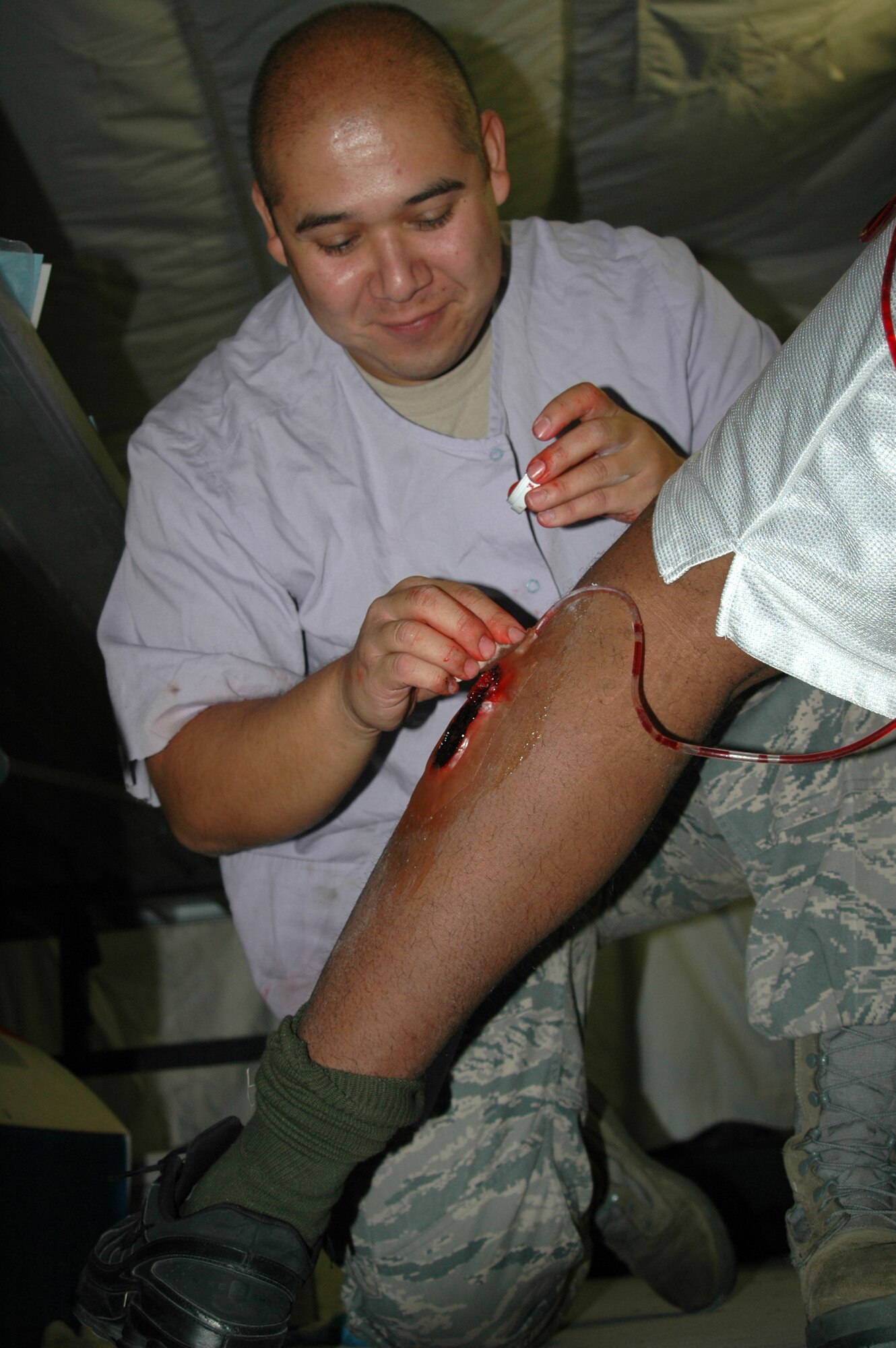 Staff Sgt. Gabriel Carbajal, 341st Medical Support Squadron unit training manager, spreads makeup on a simulated injury Sept. 17 at Camp Grizzly. This particular wound simulates arterial bleeding when a role-player squeezes a hand pump, forcing fake blood from the wound. (U.S. Air Force photo/Senior Airman Dillon White). 