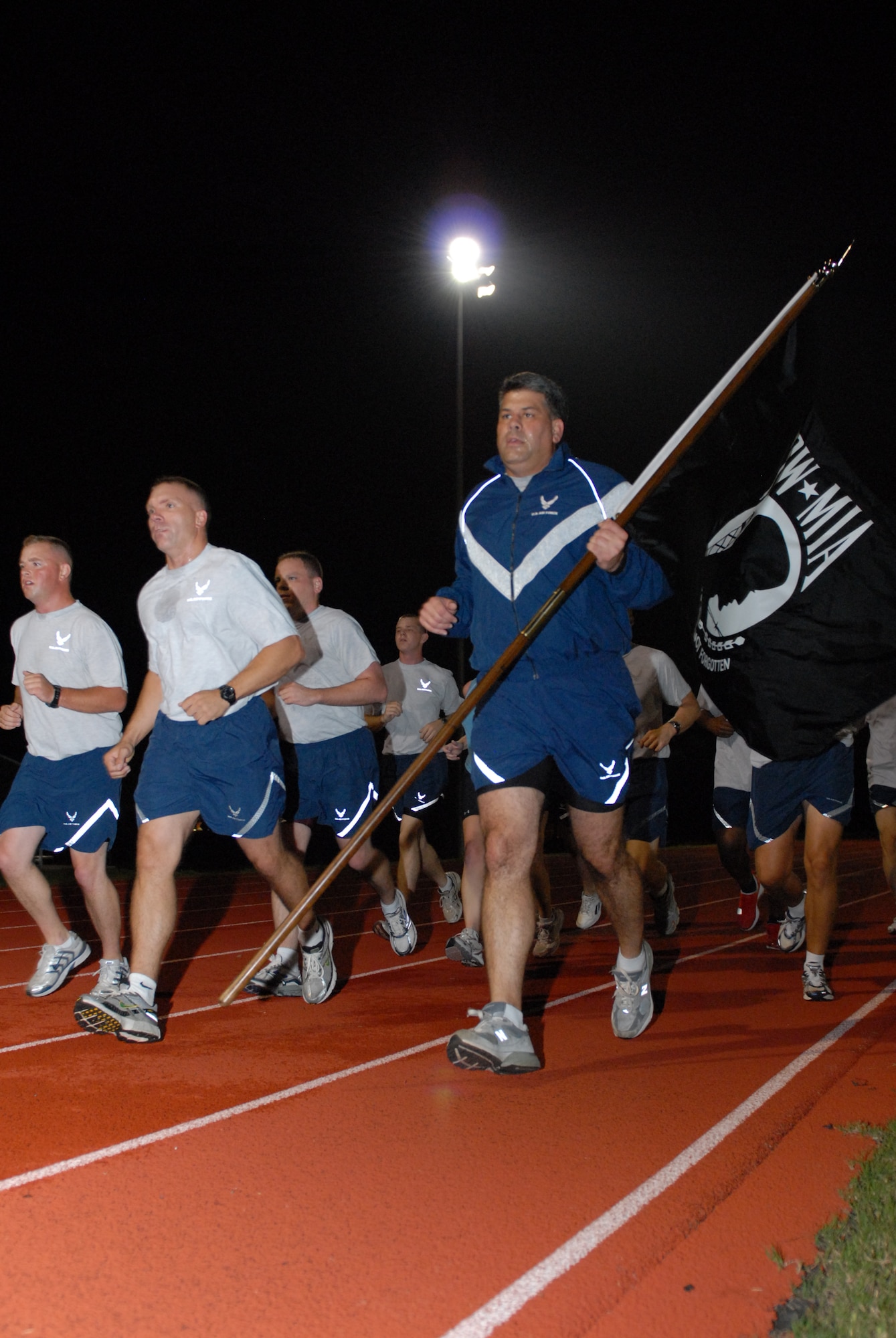 Col. Greg Otey, 19th Airlift Wing commander, carries the POW/MIA guide-on as he runs with the 53rd Airlift Squadron at the base track Sept. 18. In honor of POW/MIA recognition day, base Airmen carried the guideon while running for 24 consecutive hours - the entire duration of the day. (U.S. Air Force photo by Senior Airman Nathan Allen)