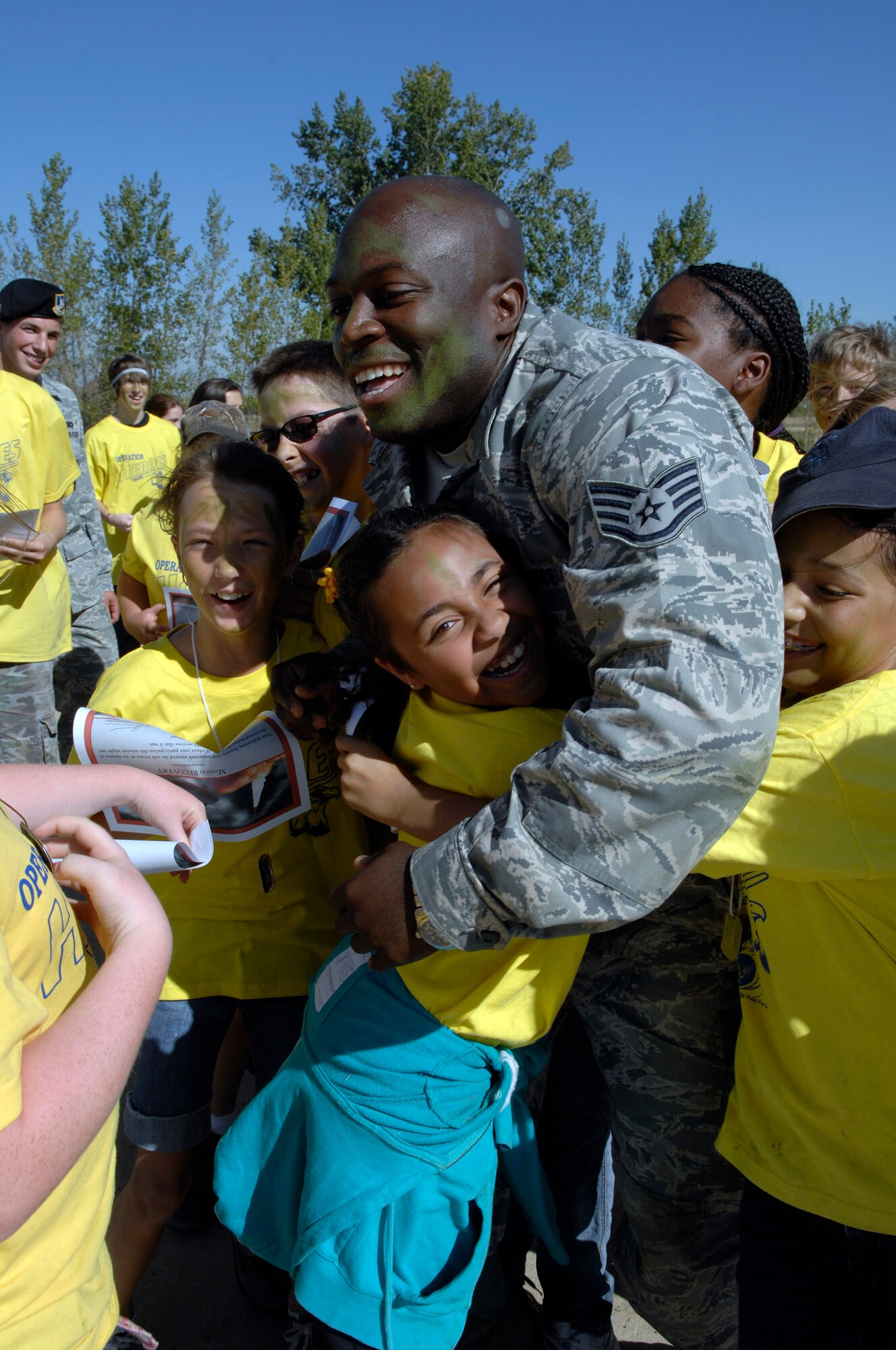 MINOT AIR FORCE BASE, N.D.—Staff Sgt. Jamell Collins, 91st Security Forces Squadron, gets hugged by kids participating in Operation Heroes here, Sept. 19.  Operations Heroes is an event for children to go through a mock deployment to simulate what their parents goes through when preparing to deploy. The older children went on a “special mission” where they learned military formation and how to detain suspects. (U.S. Air Force Photo by Senior Airman Matthew Smith)