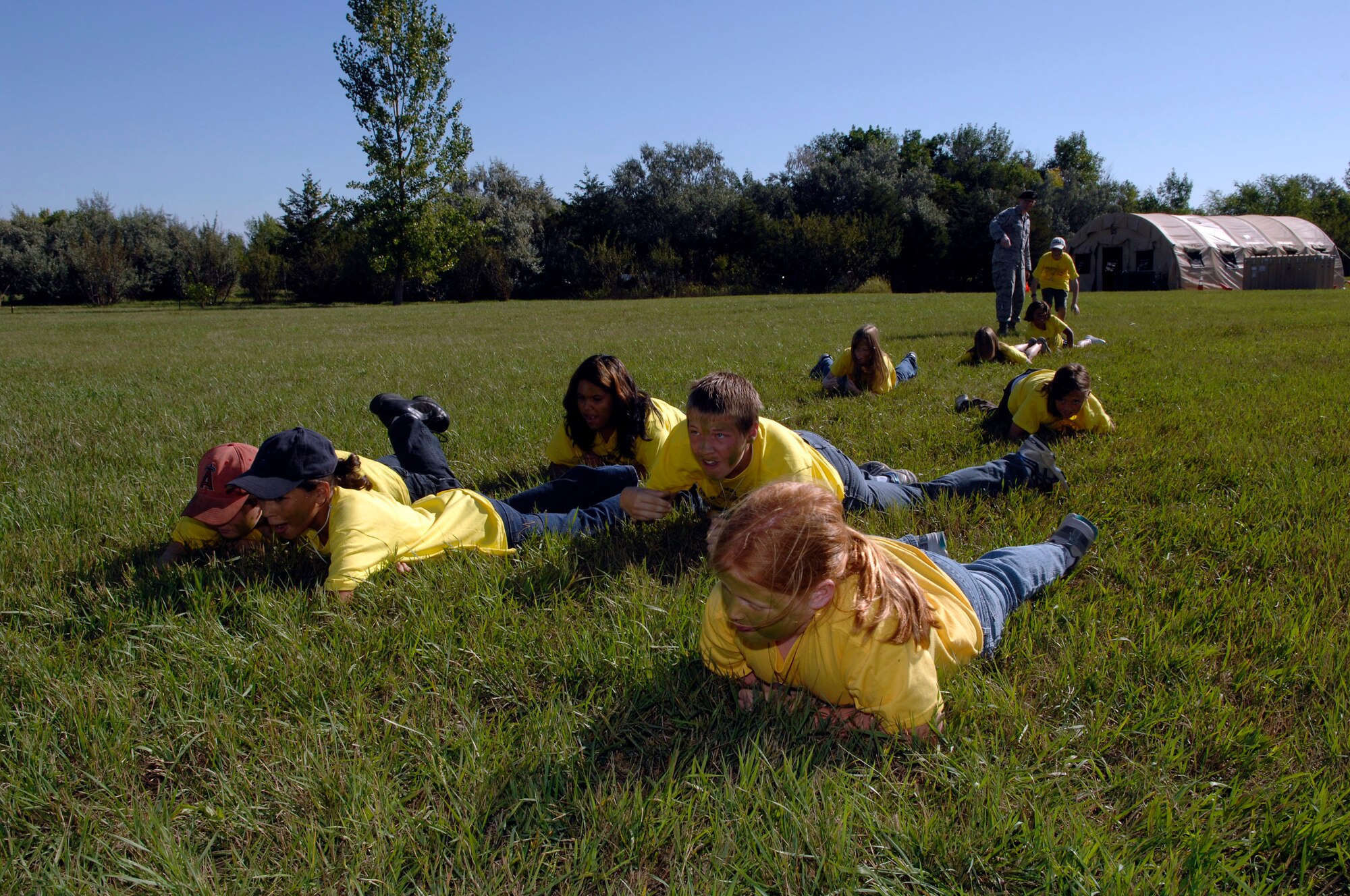 MINOT AIR FORCE BASE, N.D. -- Participants in Operation Heroes low-crawl though the grass here, Sept. 19.  Operations Heroes is an event for children to go through a mock deployment to simulate what their parents goes through when preparing to deploy. The older children went on a “special mission” where they learned military formation and how to detain suspects. (U.S. Air Force Photo by Senior Airman Matthew Smith)