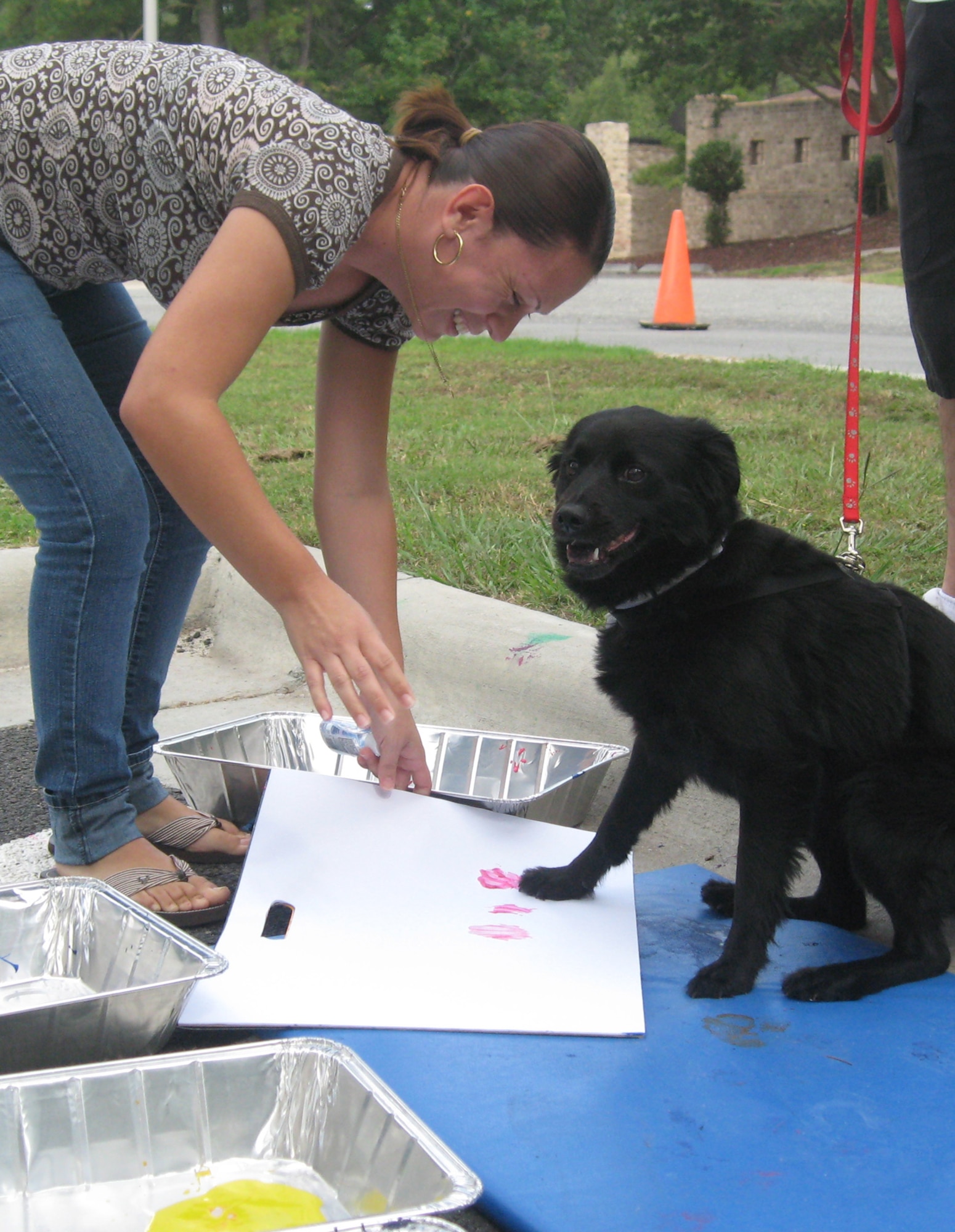 Yecenia Cosme helps her dog, Negrita, with a paw painting at the Pet Fair hosted by the Southern Pines Inn on Seymour Johnson Air Force Base, N.C., Sept. 19, 2009. Mrs. Cosme is the wife of Tech. Sgt. Juan Cosme, 4th Aircraft Maintenance Squadron load crew chief. The fair featured adoption booths from Diamonds in the Ruff and the Wayne County Animal Shelter in Goldsboro, educational information, micro chipping, patriotic pet photos and more.  (U.S. Air Force photo by Tech. Sgt. Tammie Moore)