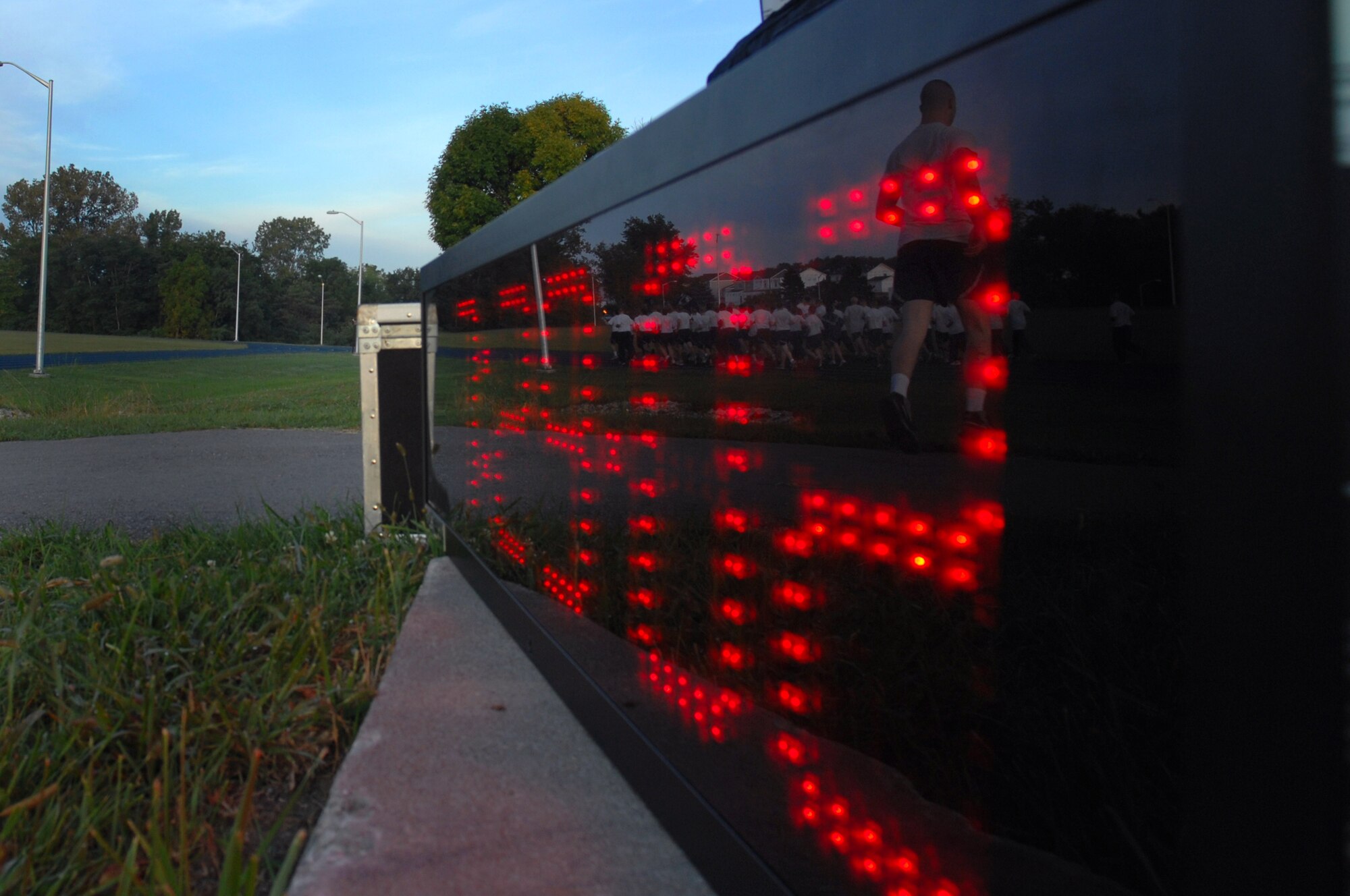 WHITEMAN AIR FORCE BASE, Mo. - Images of members with the 509th Maintenance Group running during their leg of the POW/MIA run are shown reflected in the time clock as the strive to keep the POW/MIA torch and flag moving, Sept. 18. The POW/MIA run is a 24-hour torch and flag run to honor prisoners of war and missing-in-action personnel. Staff Sgts. Amir Hasan and Brandon Lines, 509th Munitions Squadron, organized the 24-hour run and scheduled it to kick off at 6 a.m. the morning of the Air Forces 62nd anniversary. Several military and civilian personnel from 24 different organizations participated in the run. (U.S. Air Force photo/Senior Airman Kenny Holston)