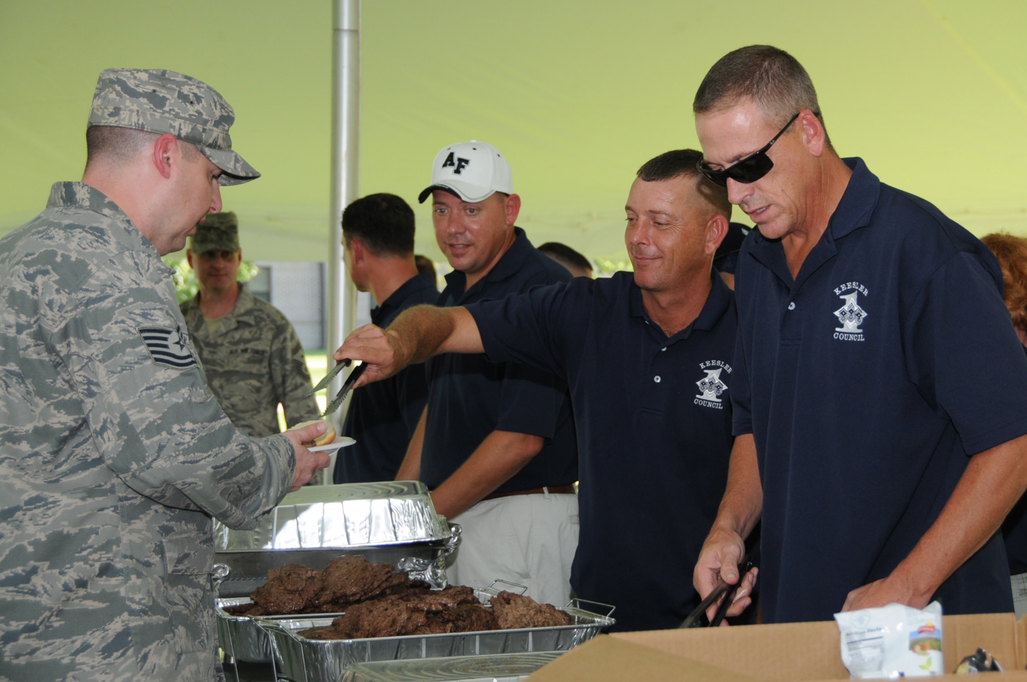 From left, Tech. Sgt. Barney Roberts, 335th Training Squadron, passes down the serving line as first sergeants Master Sgts. Christopher Rash, 81st Security Forces Squadron, and Scott Passman, 335th TRS, and Senior Master Sgt. John Geboy, 336th TRS, pass out free hot dogs and burgers.  (U.S. Air Force photo by Kemberly Groue)